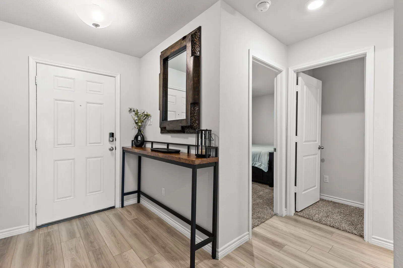 Entryway featuring wood-finish flooring, a contemporary console table, and a decorative mirror
