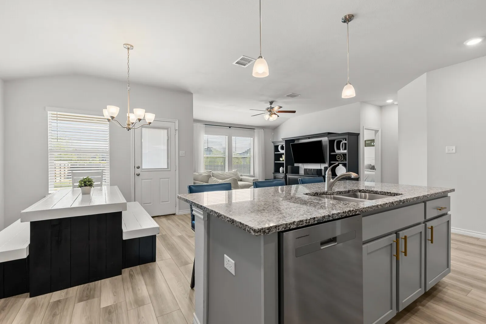 Kitchen island with a stainless steel sink and faucet, integrated dishwasher, and granite countertop