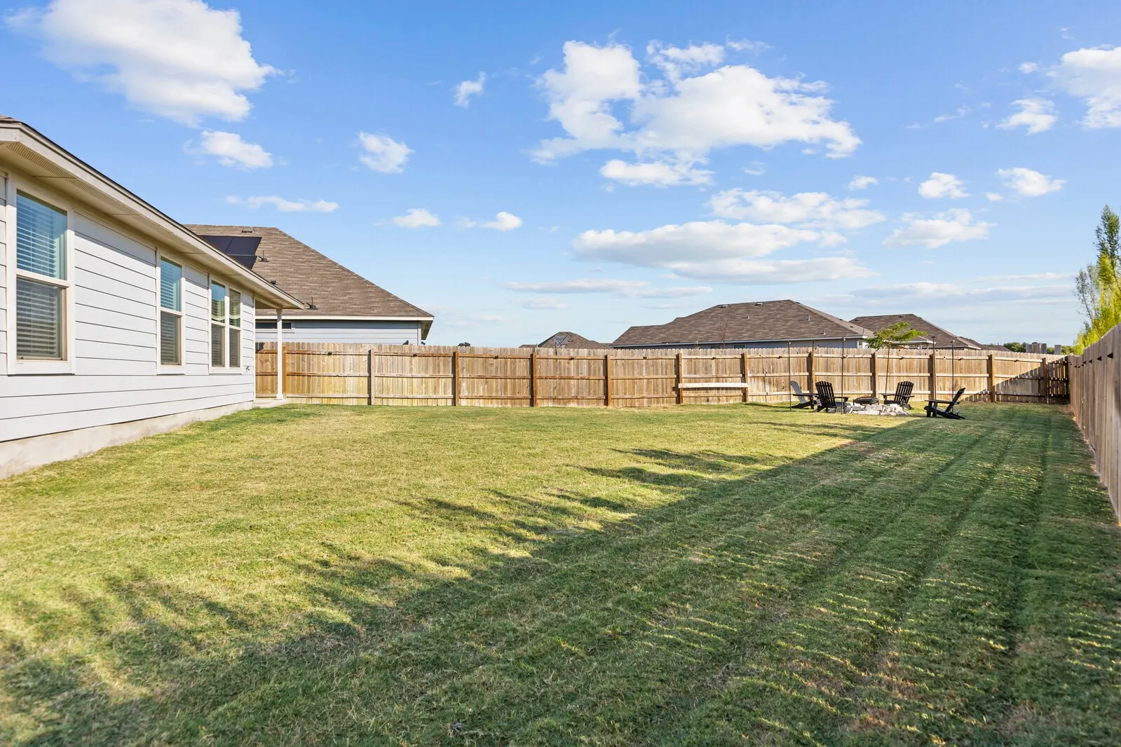 Expansive green space featuring a wood fence, siding exterior, and multiple windows