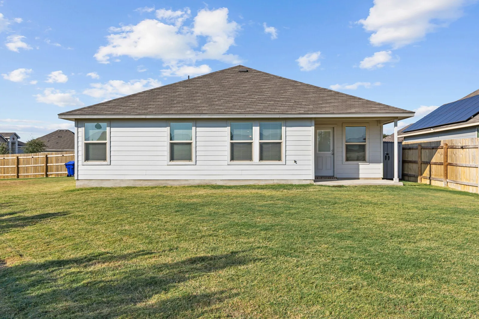 Expansive backyard with a flat lawn, privacy fencing, and a concrete patio