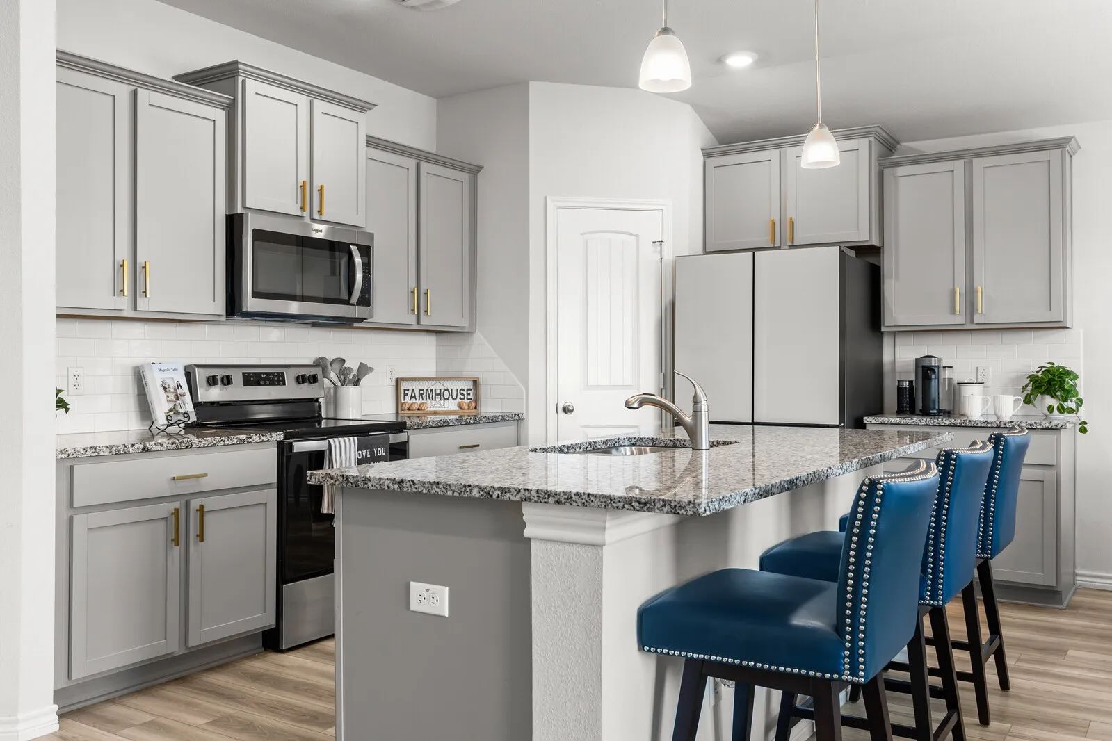 Kitchen featuring light gray cabinetry, stainless steel appliances, granite countertops, an undermount sink, and wood-finish flooring