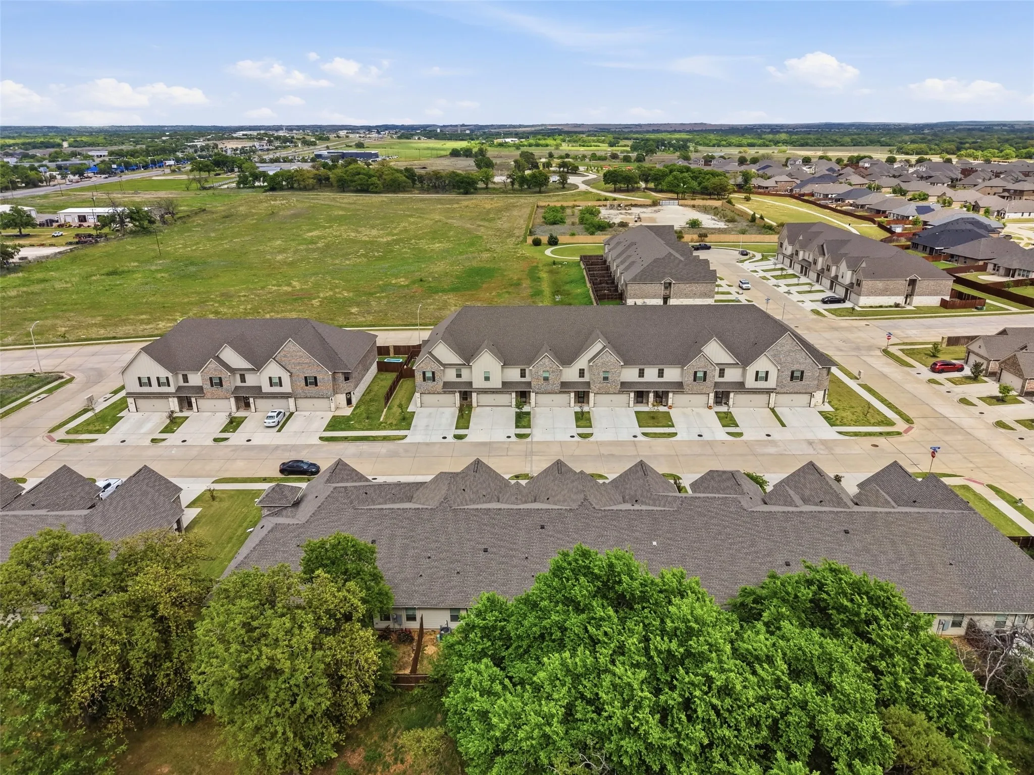 Contemporary townhome development featuring brick and siding exteriors, attached garages, and paved driveways