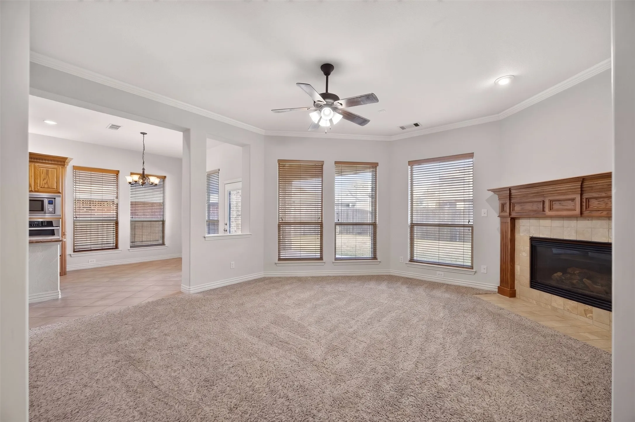 Living area with a fireplace featuring a wood mantel, an integrated ceiling fan, and multiple windows