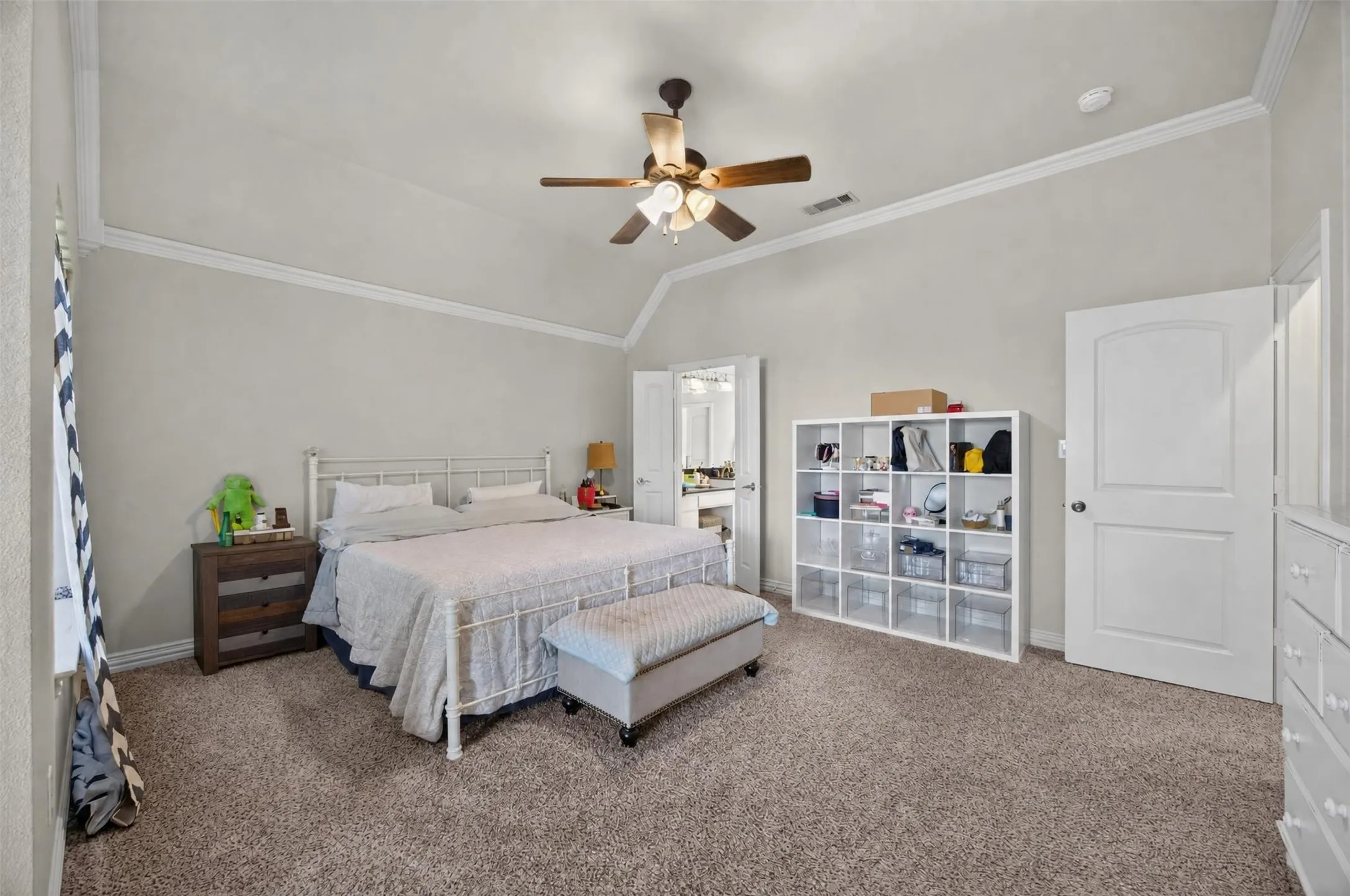Vaulted ceiling with crown molding, ceiling fan, and carpeted flooring