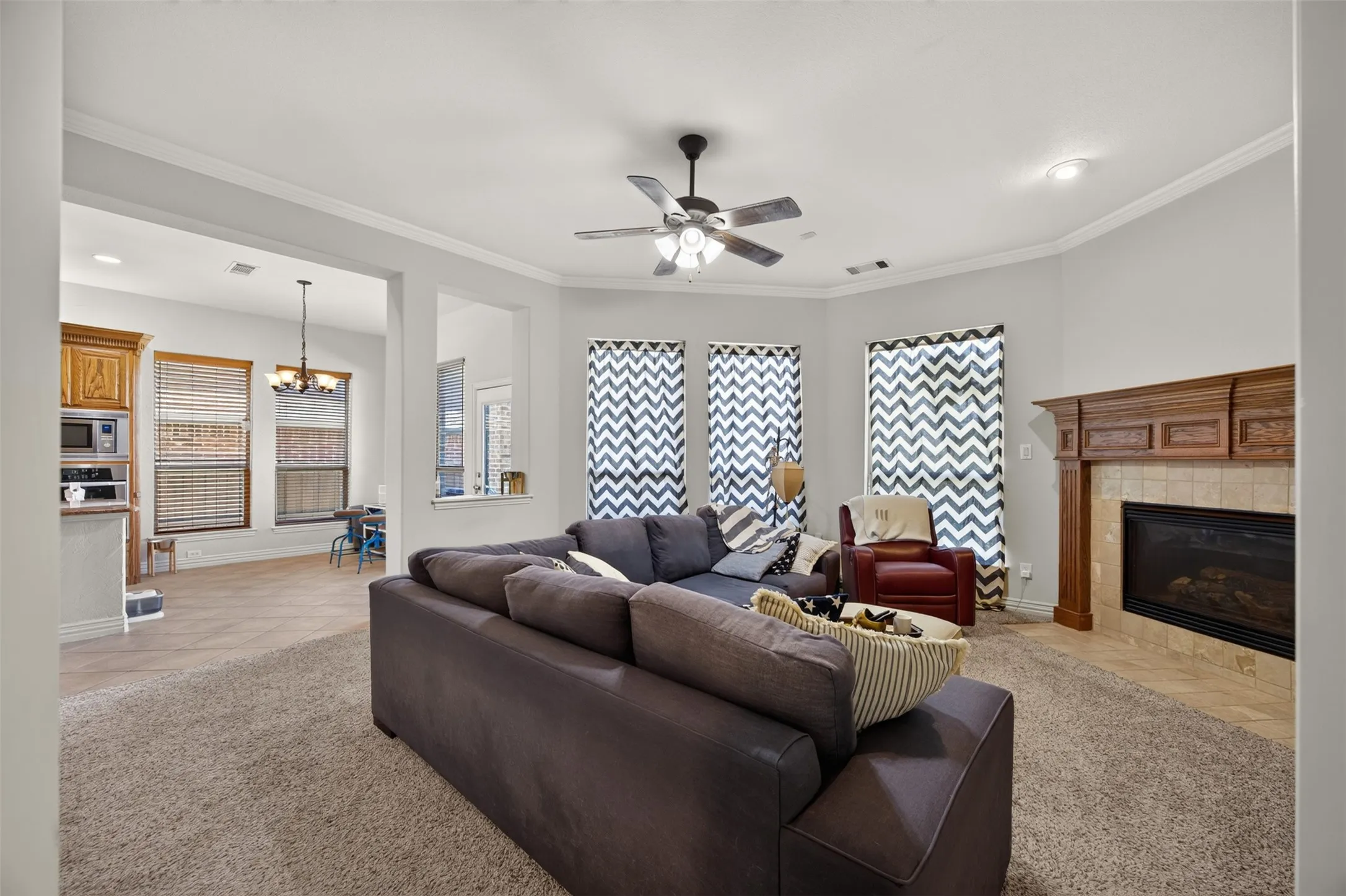 Carpeted living area featuring a built-in fireplace with a wood mantel, recessed lighting, and a ceiling fan