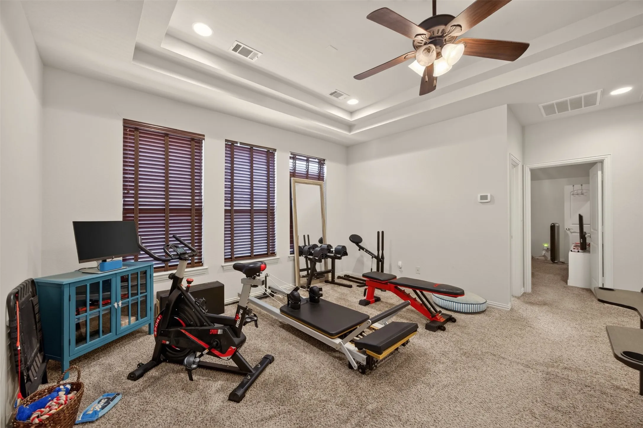 Recessed lighting, ceiling fan, tray ceiling, carpeted flooring, and window blinds