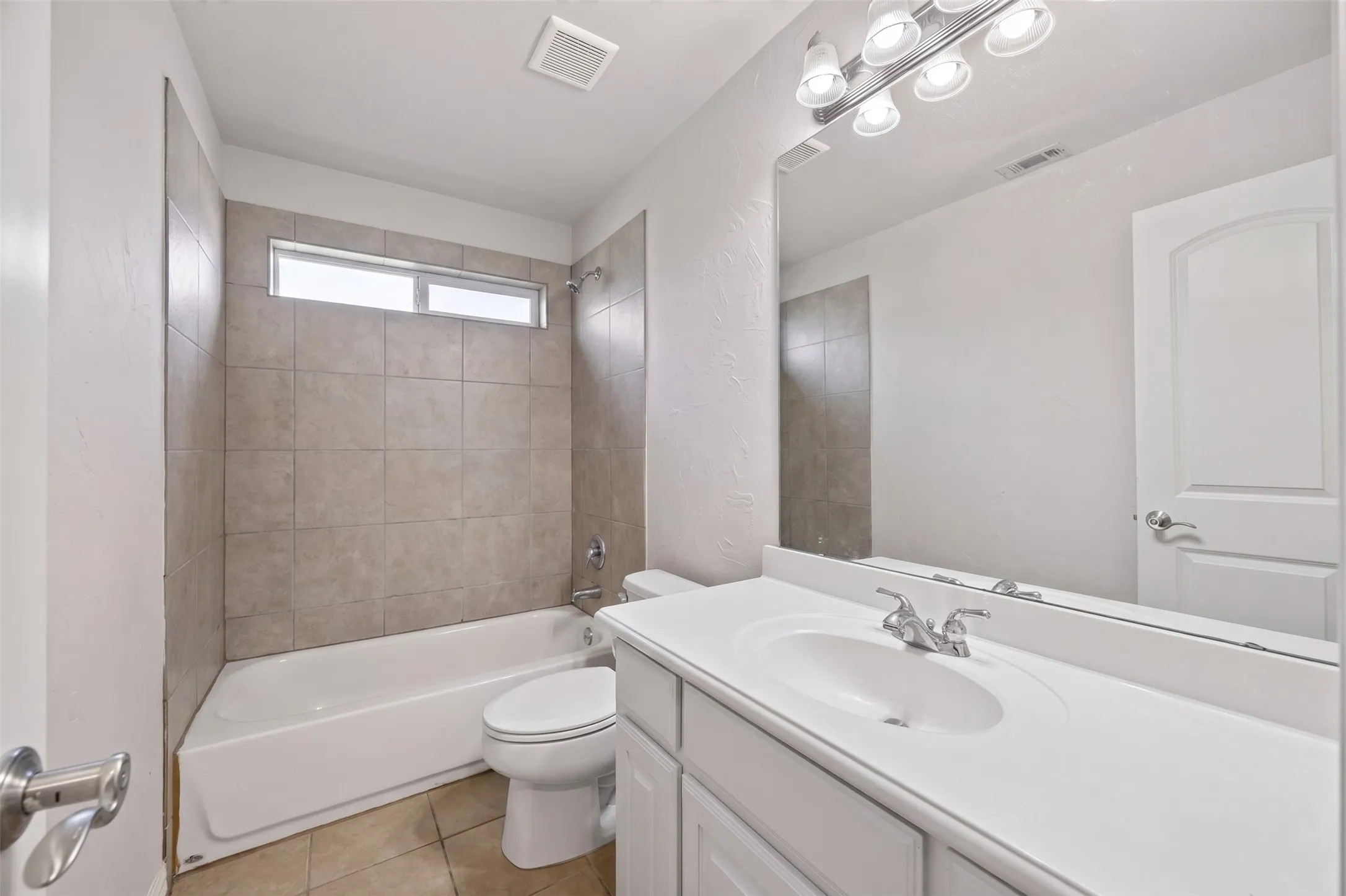 Bathroom featuring a white vanity with an integrated sink, polished chrome faucet, and a large wall-mounted mirror