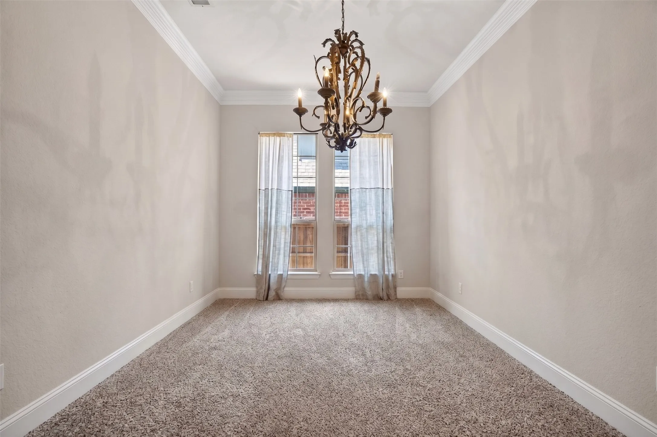 Chandelier lighting, crown molding, neutral wall finishes, plush carpeting, and window with natural light