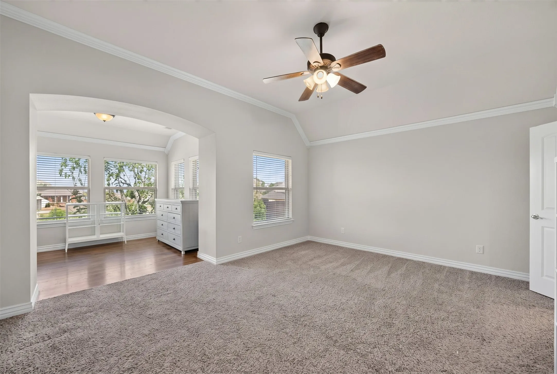Vaulted ceiling with a ceiling fan, arched doorway, wood-finish flooring, recessed lighting, and multiple windows with blinds