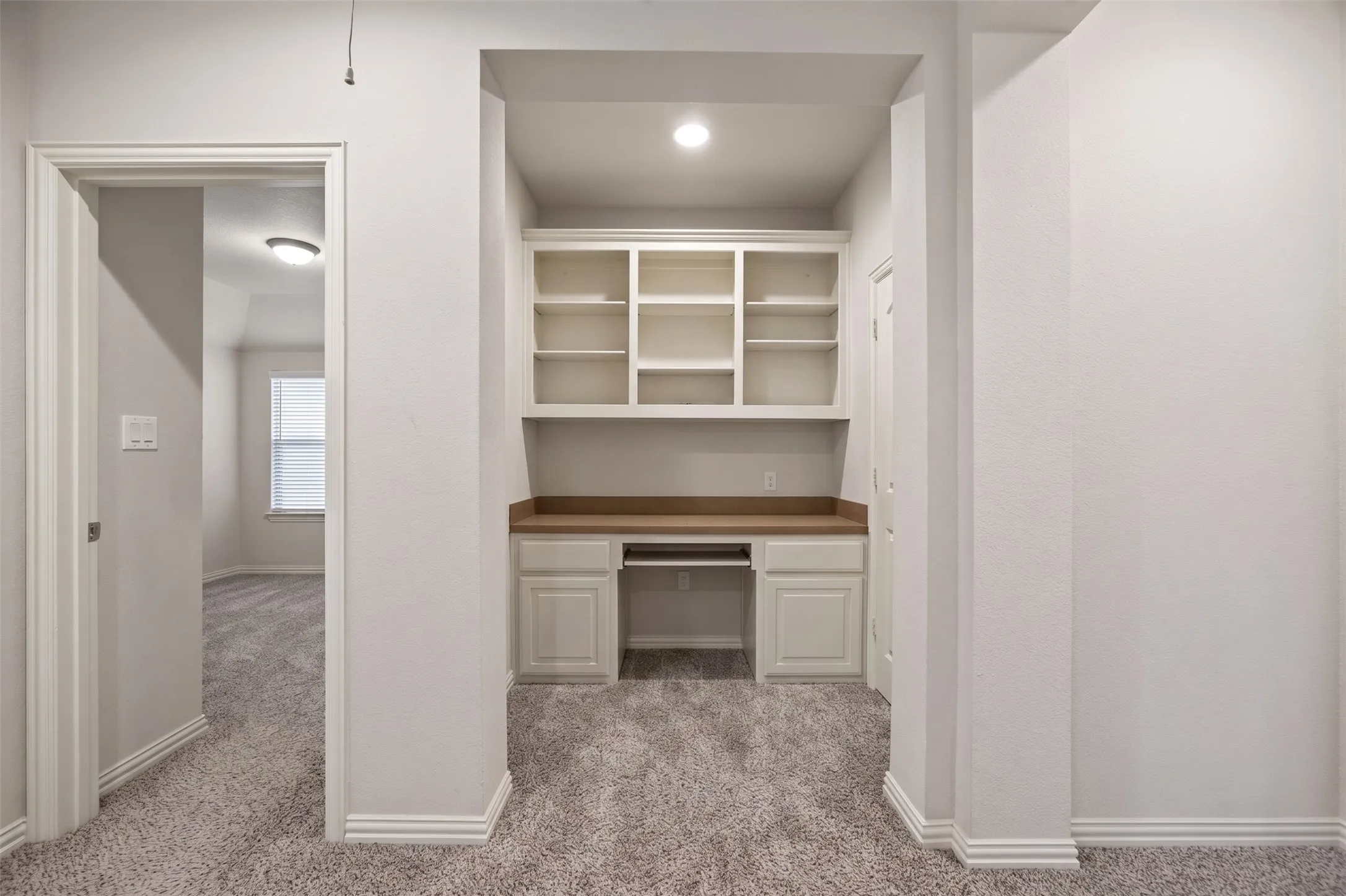 Built-in desk with overhead shelving, recessed lighting, and carpet flooring