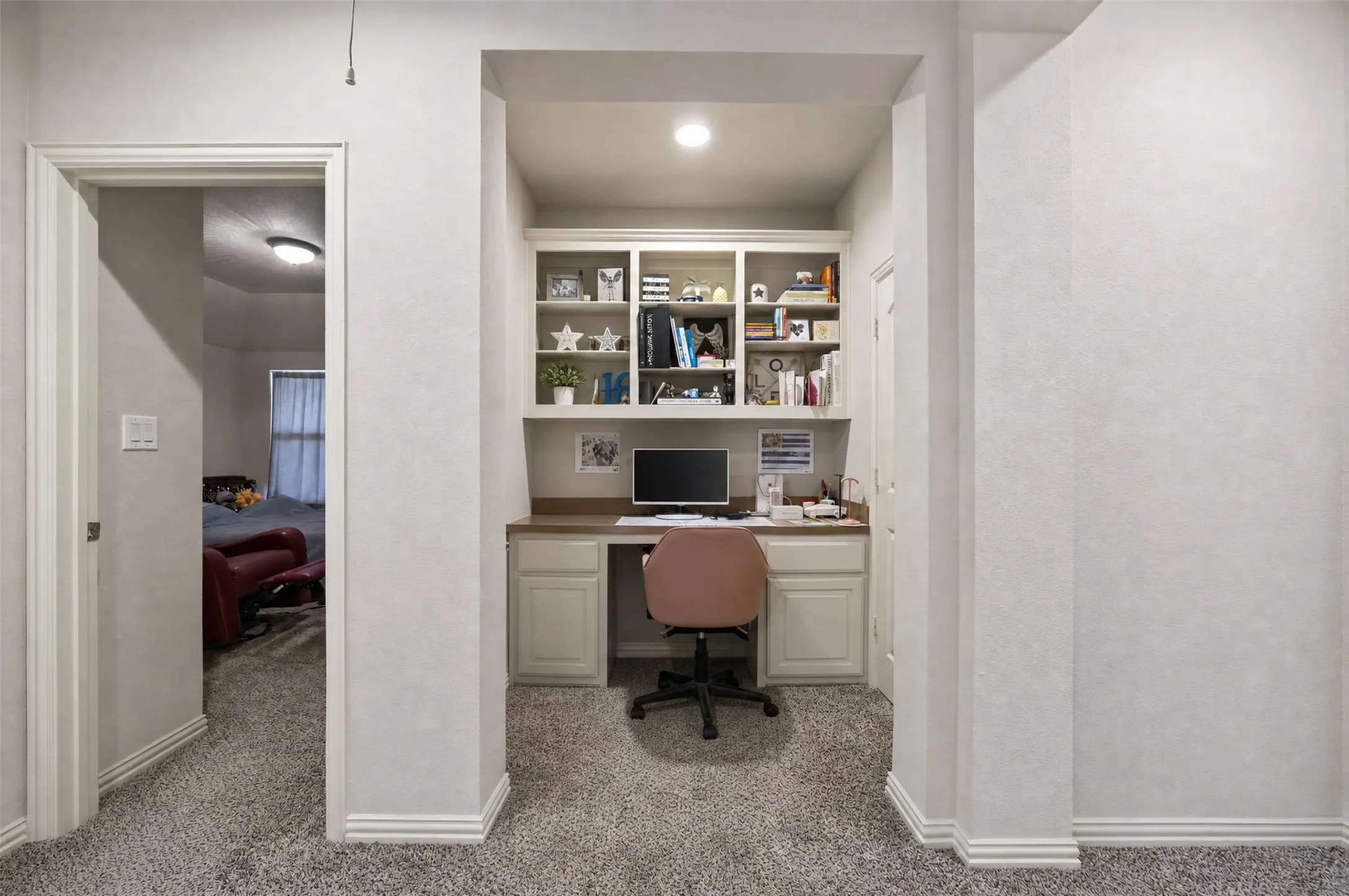 Built-in desk area featuring integrated cabinetry and shelving, recessed lighting, and carpet flooring