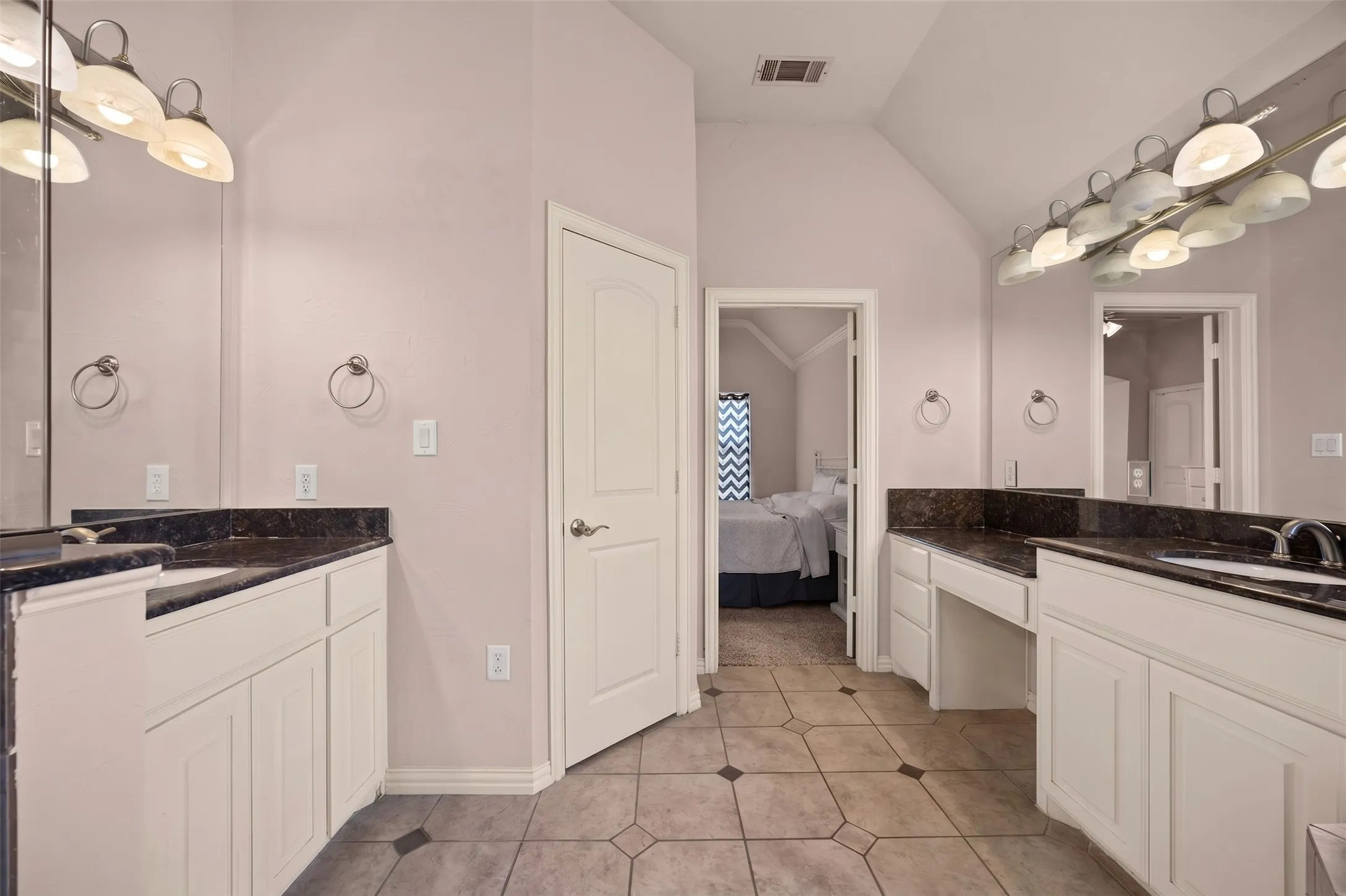 Dual vanity with dark stone countertops, individual sinks, and a dedicated makeup counter