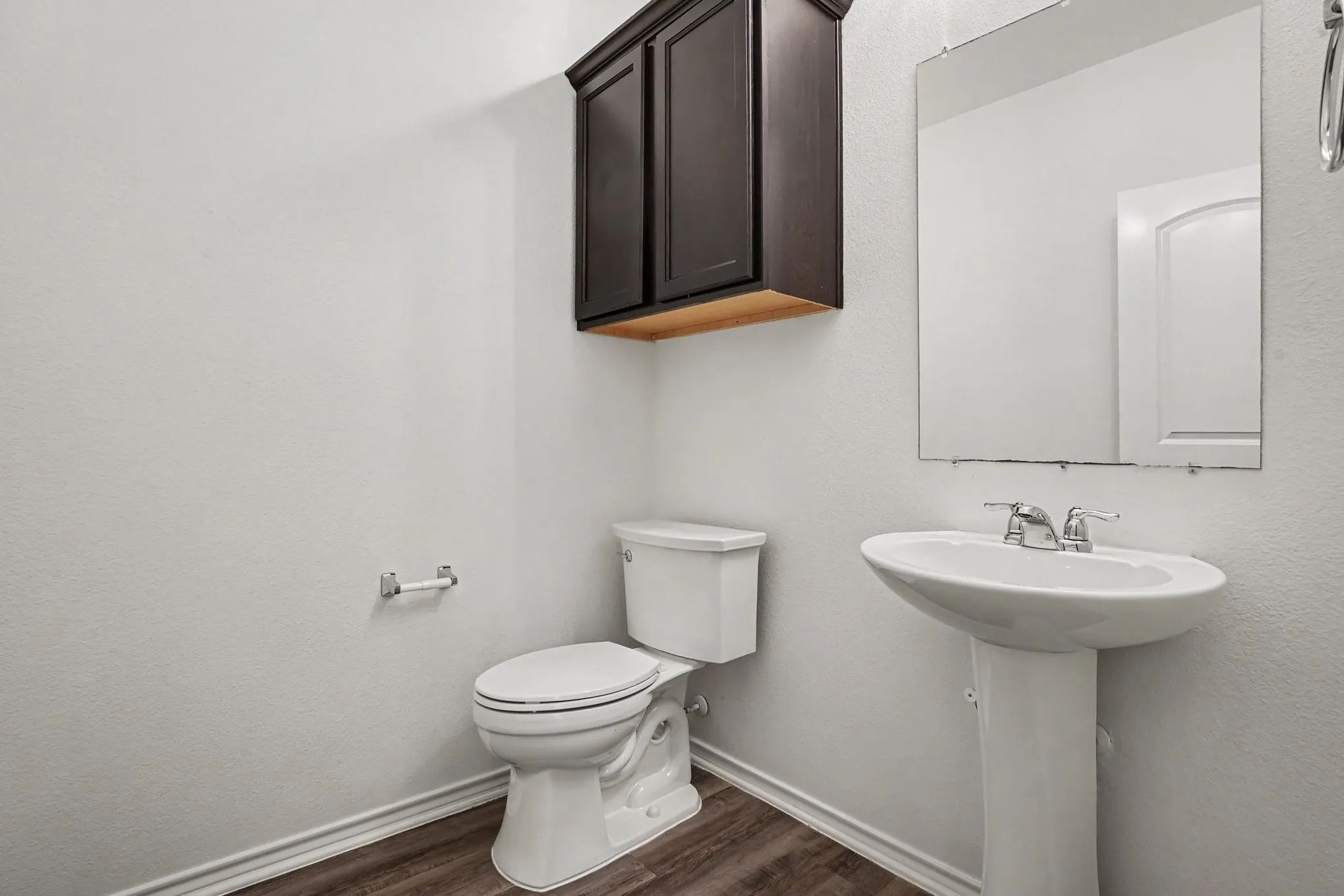 A convenient half bath with a pedestal sink and wall-mounted storage.