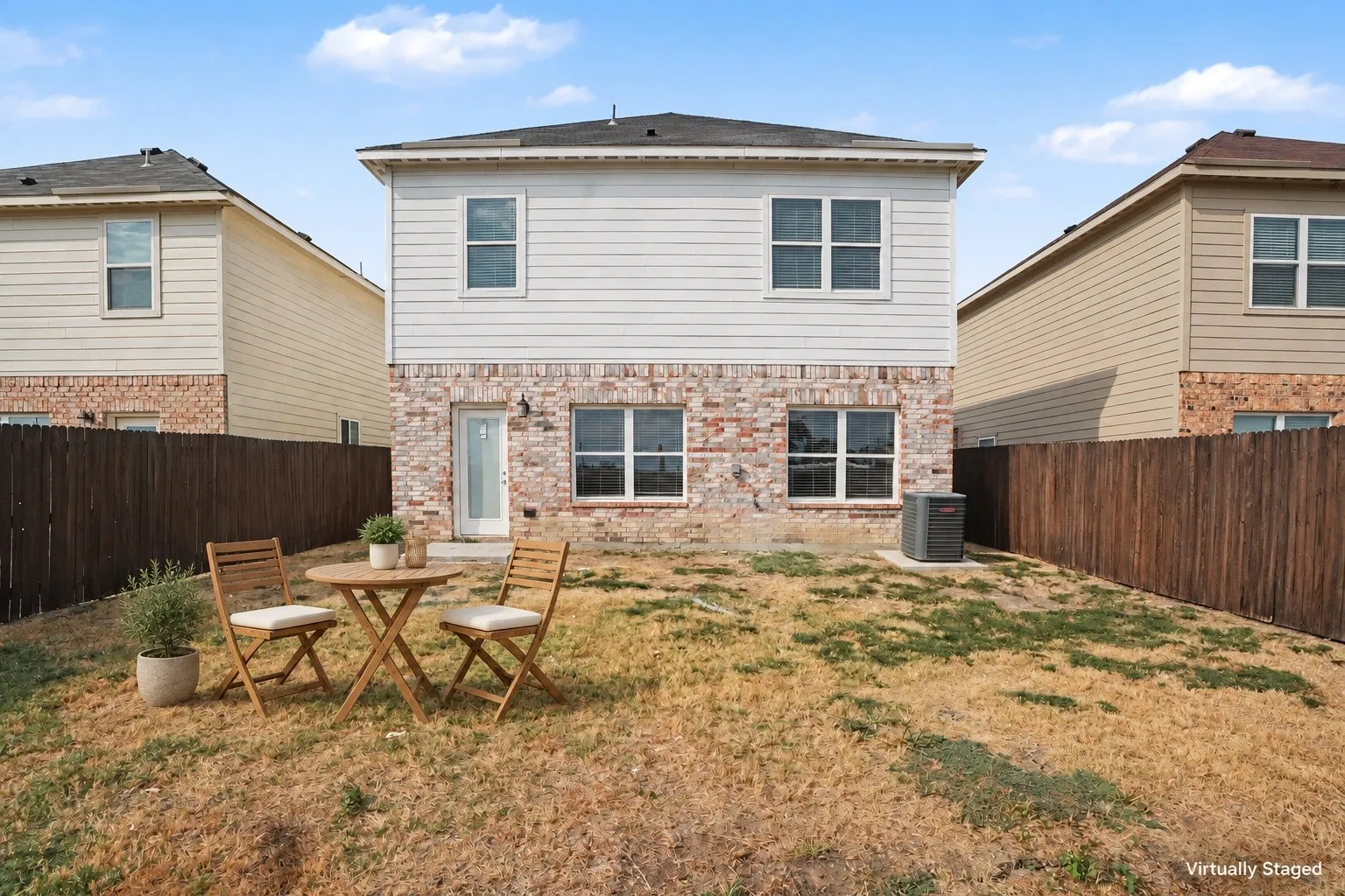 Virtually staged with outdoor furniture to illustrate a simple seating area. The fenced backyard offers space to relax outdoors.