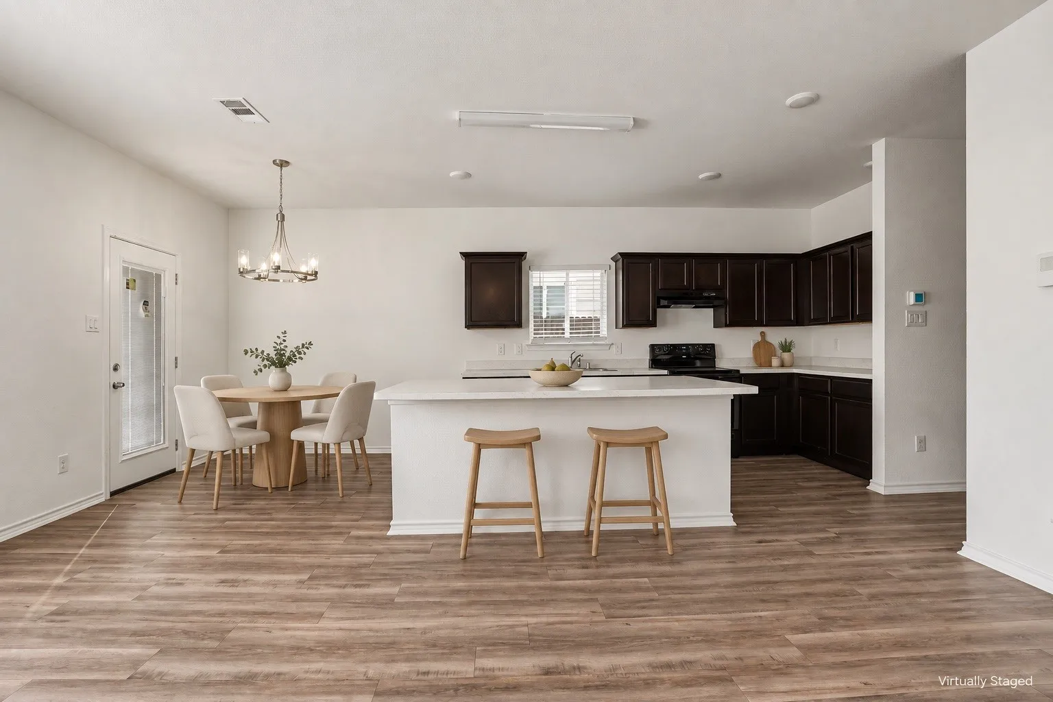 Virtually staged. The kitchen island offers casual seating, with a dining area beside the back door.