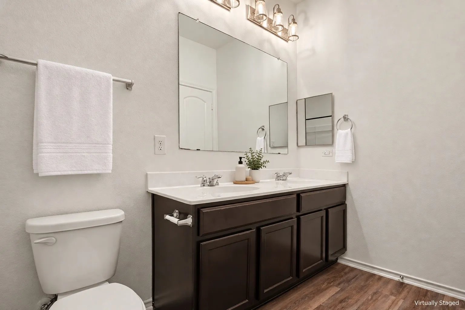 Virtually staged with decorative accessories. This bathroom features a double vanity, generous mirror and cabinet storage.