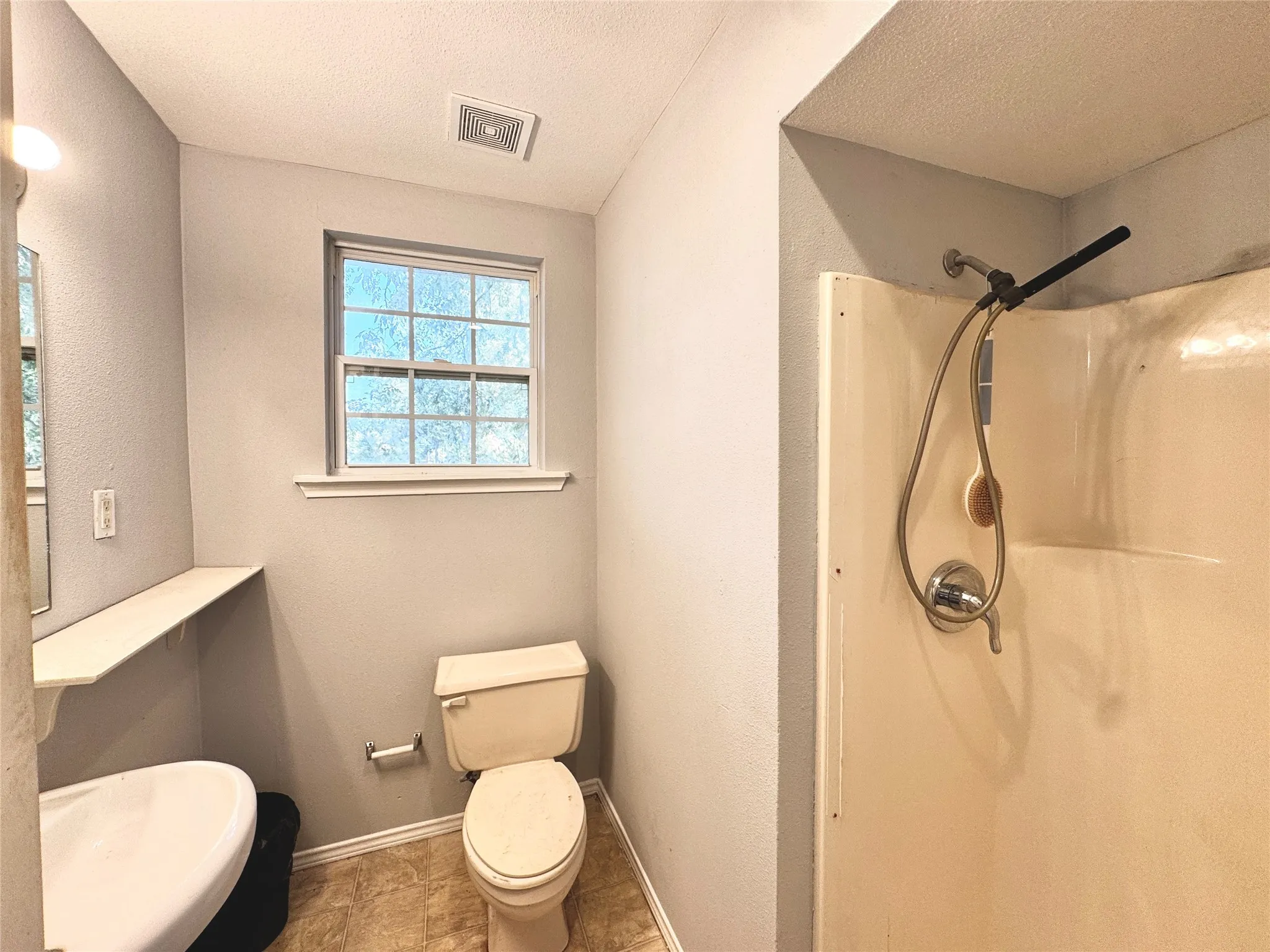 Bathroom with a window, single vanity, and a shower stall