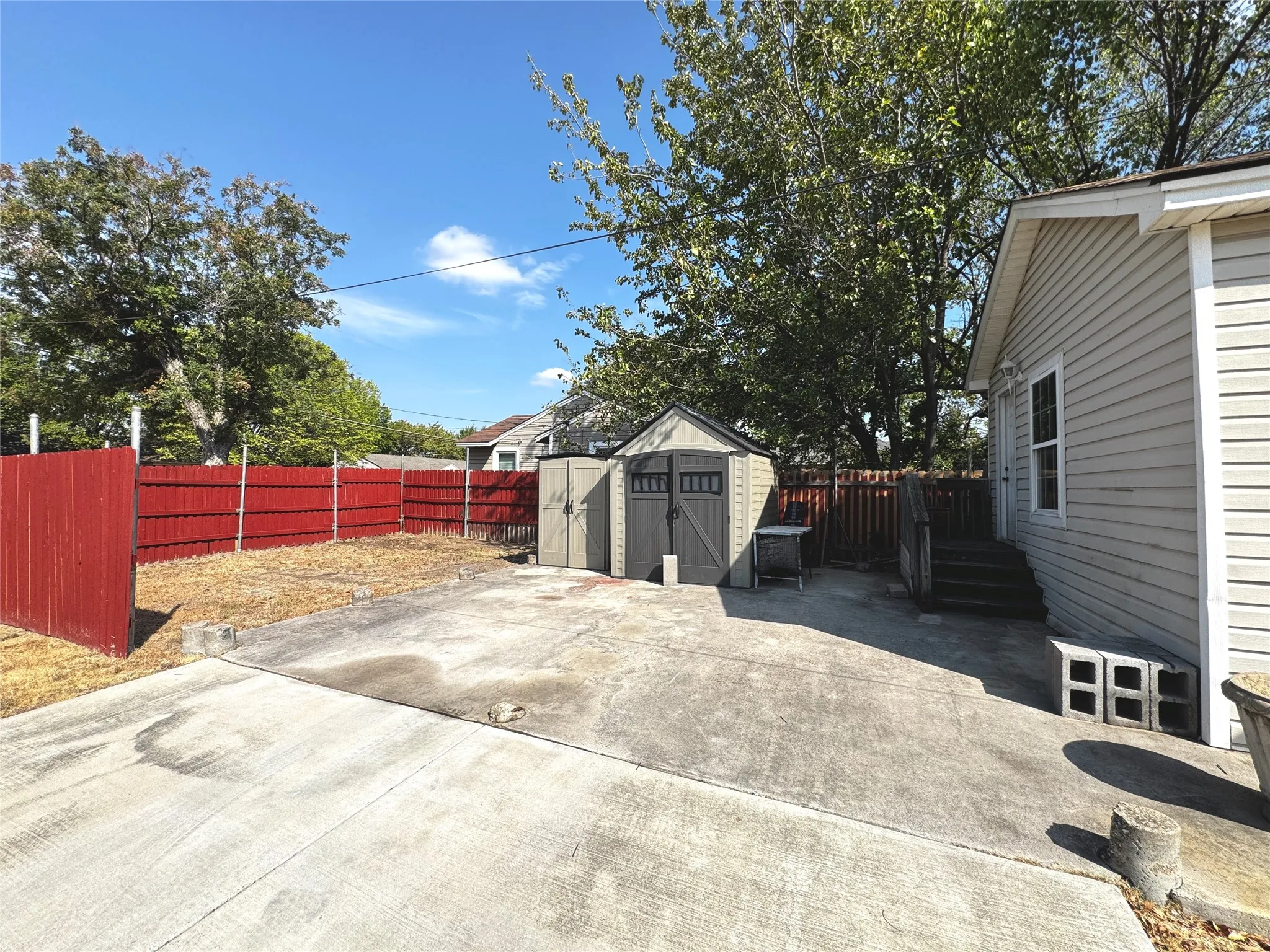 Concrete patio with a storage shed, fenced yard, and exterior siding