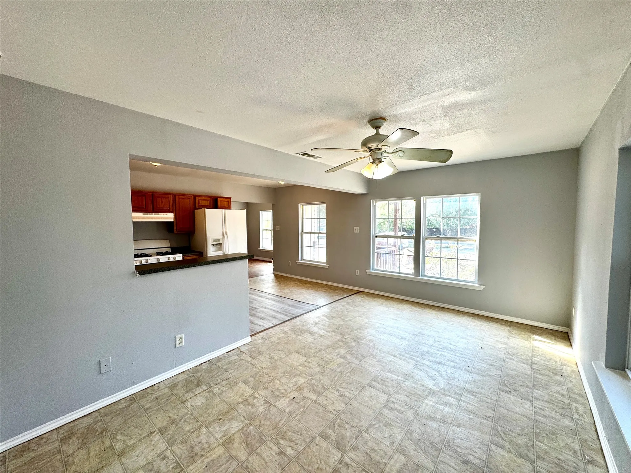 Open-concept common area featuring a ceiling fan, multiple windows, and a pass-through counter to the kitchen