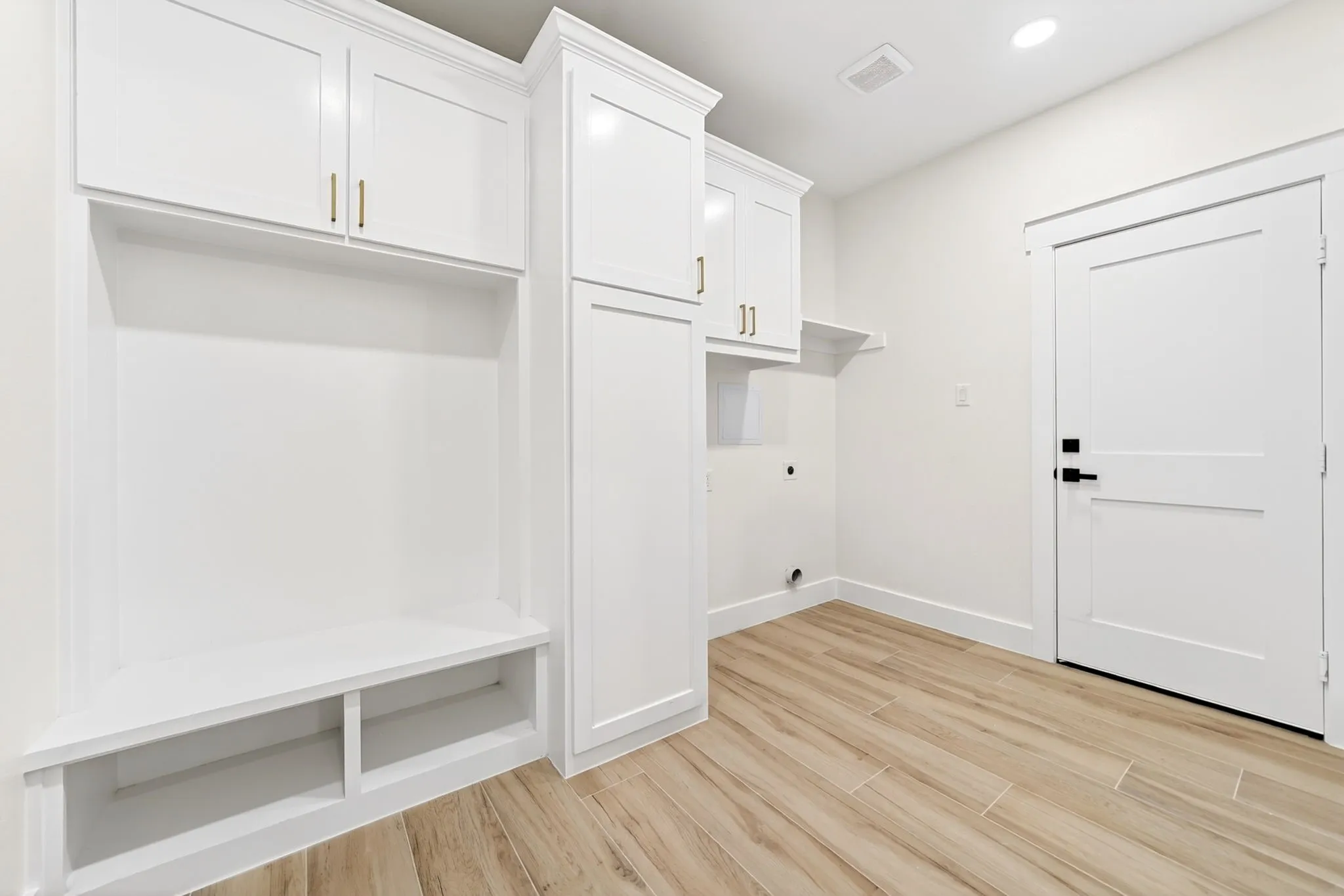 Integrated built-in storage, white shaker-style cabinetry with gold-tone hardware, wood-finish flooring, and recessed lighting