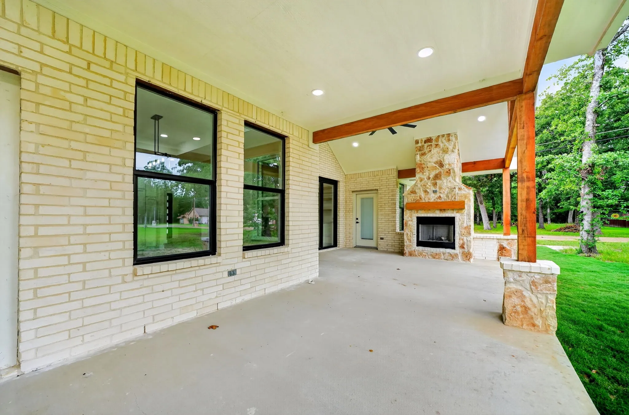 Covered patio with a stone-clad fireplace and wood mantel