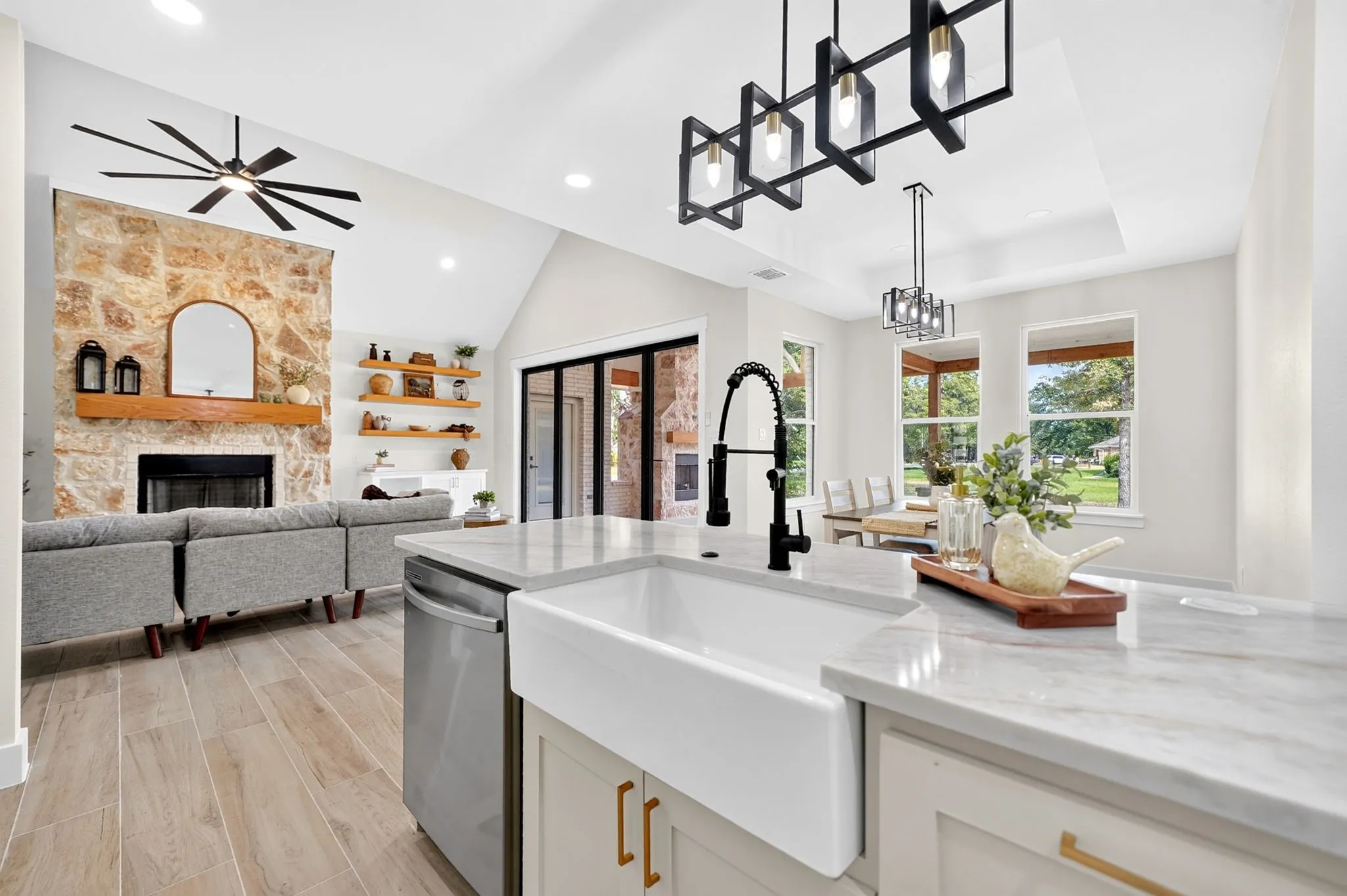 Spacious kitchen island with a farmhouse sink, stainless steel dishwasher, and stone-finish countertops