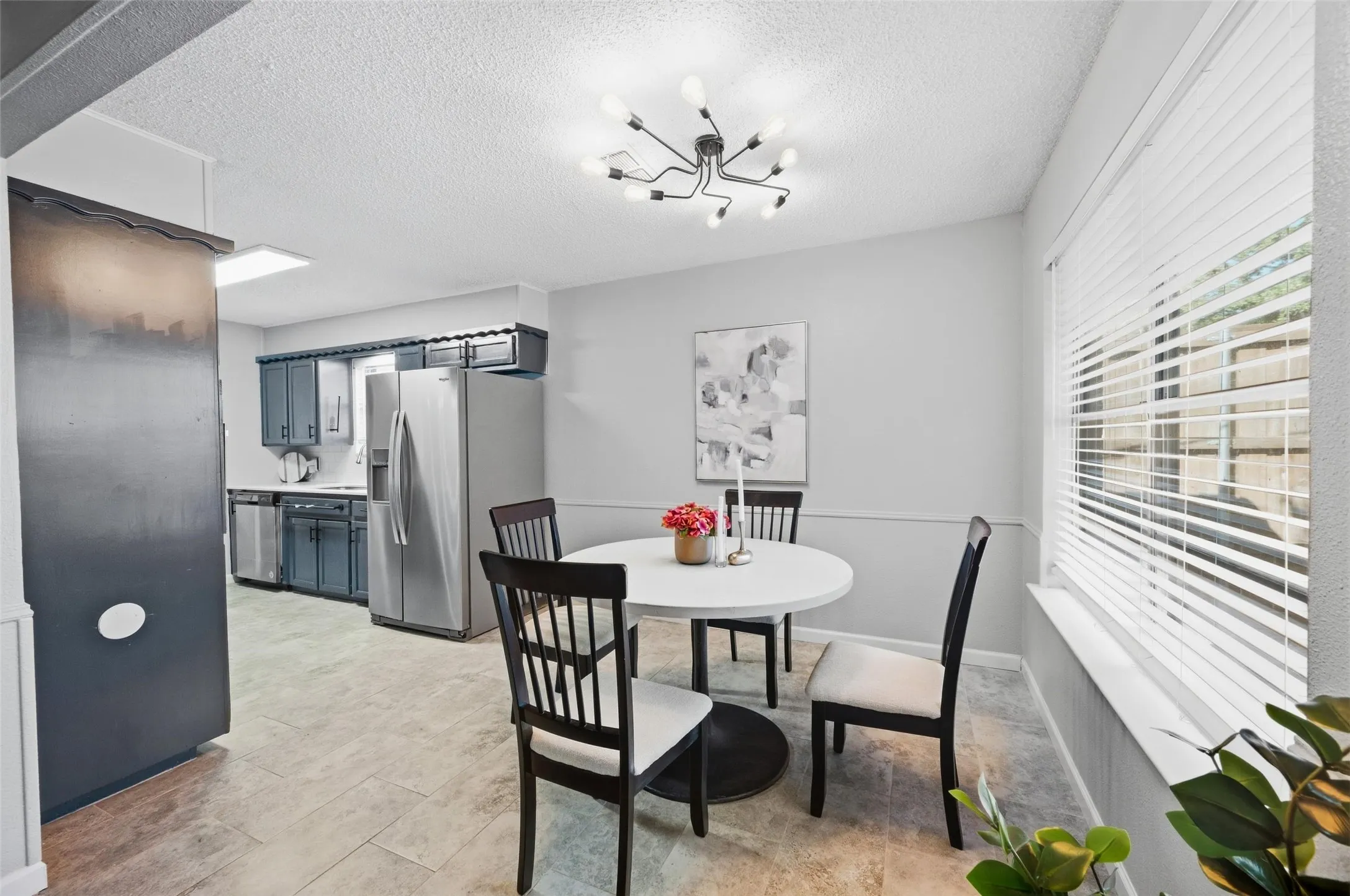 Dining area with a contemporary sputnik-style light fixture, a window with horizontal blinds, and a chair rail