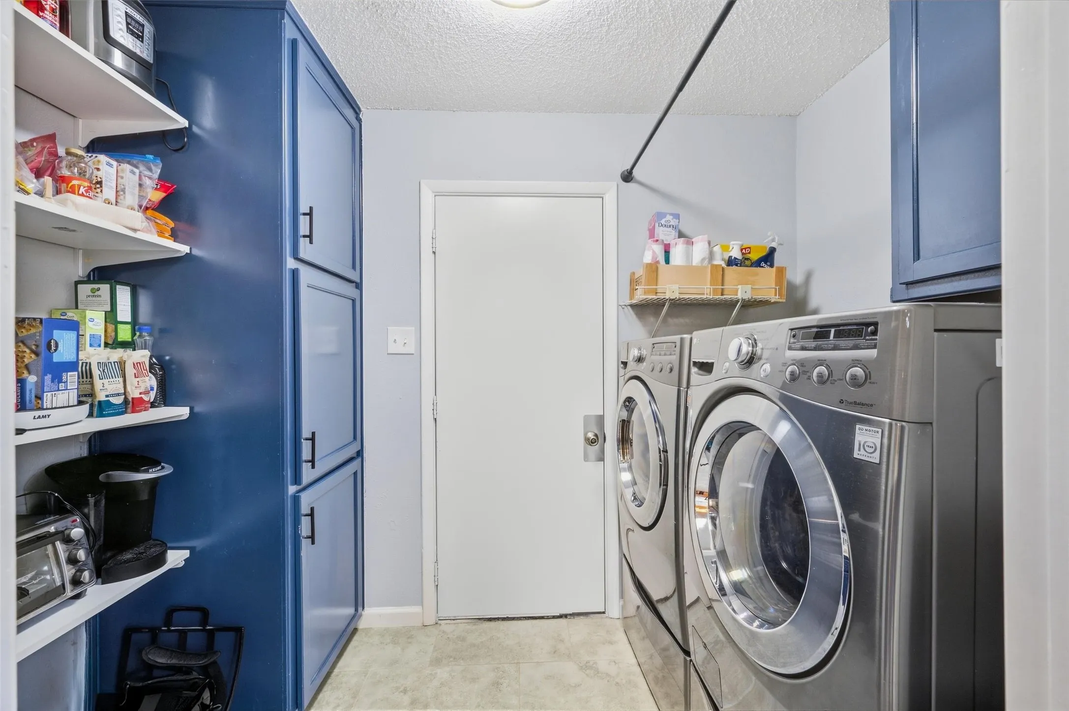 Built-in shelving, blue cabinetry with dark hardware, and a hanging rod