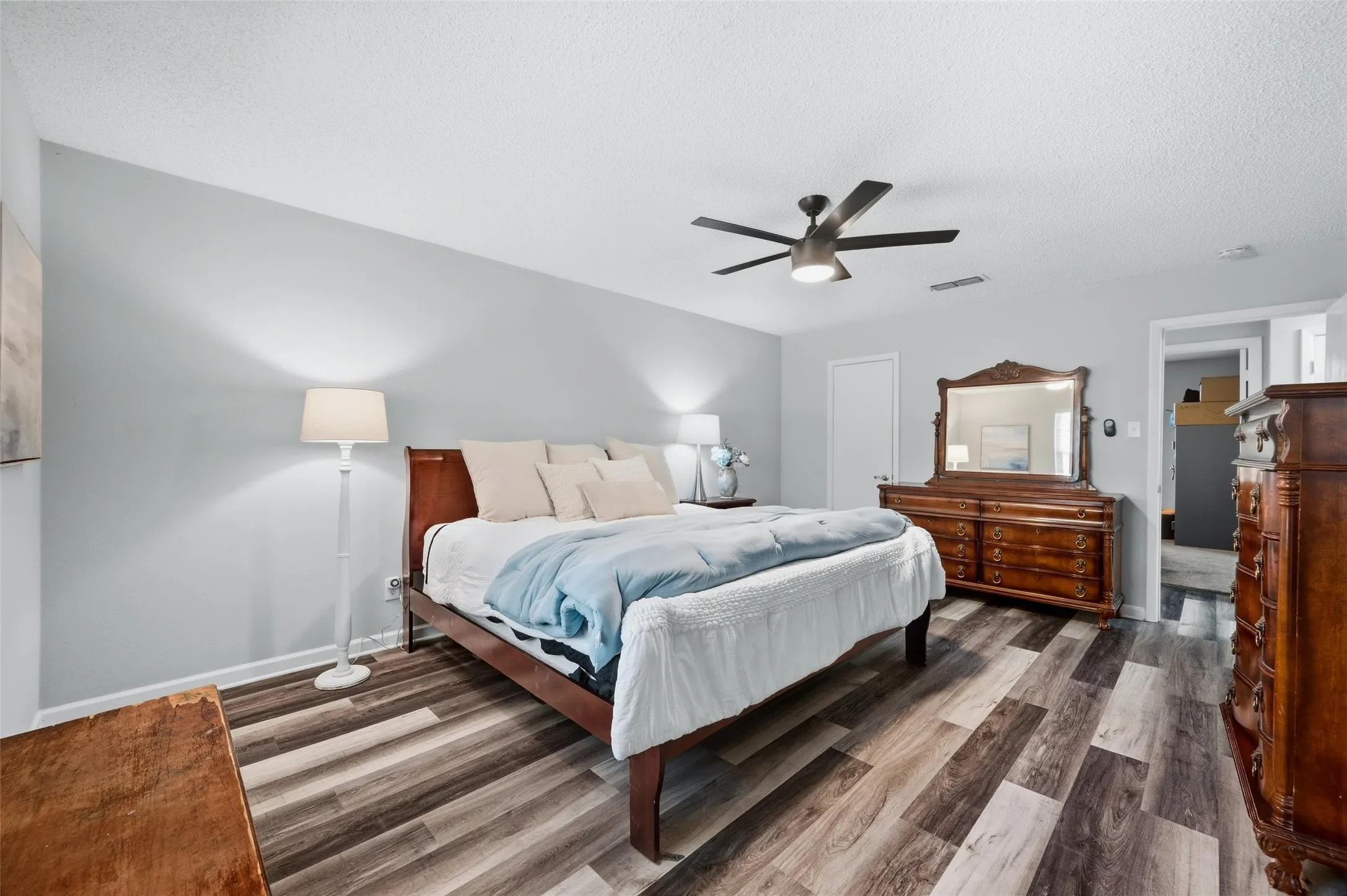 Spacious room featuring wood-finish flooring, light gray wall paint, and a ceiling fan with integrated lighting