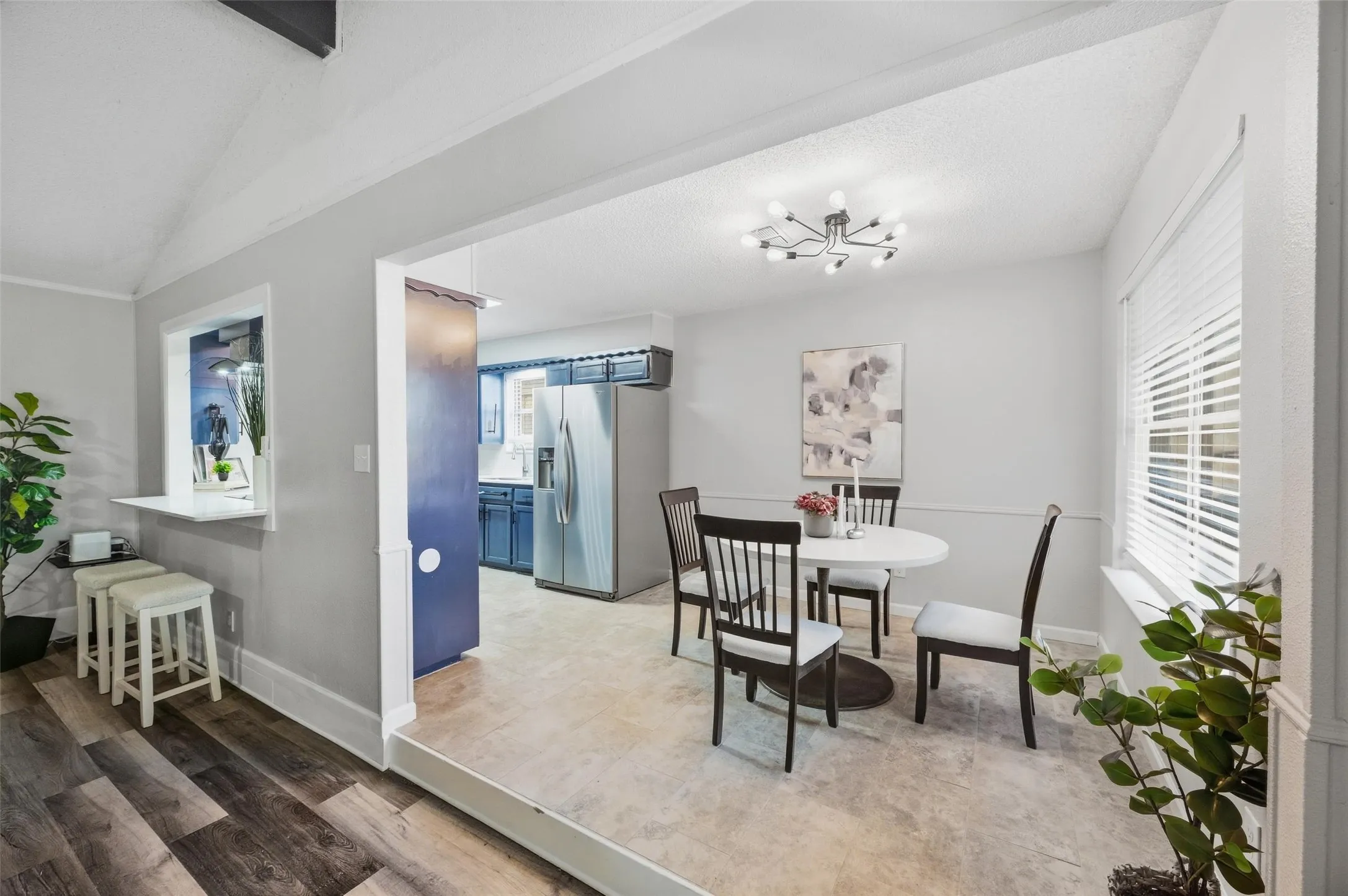 Wood-finish flooring, pass-through window with counter seating, recessed entryway, contemporary light fixture, and horizontal blinds