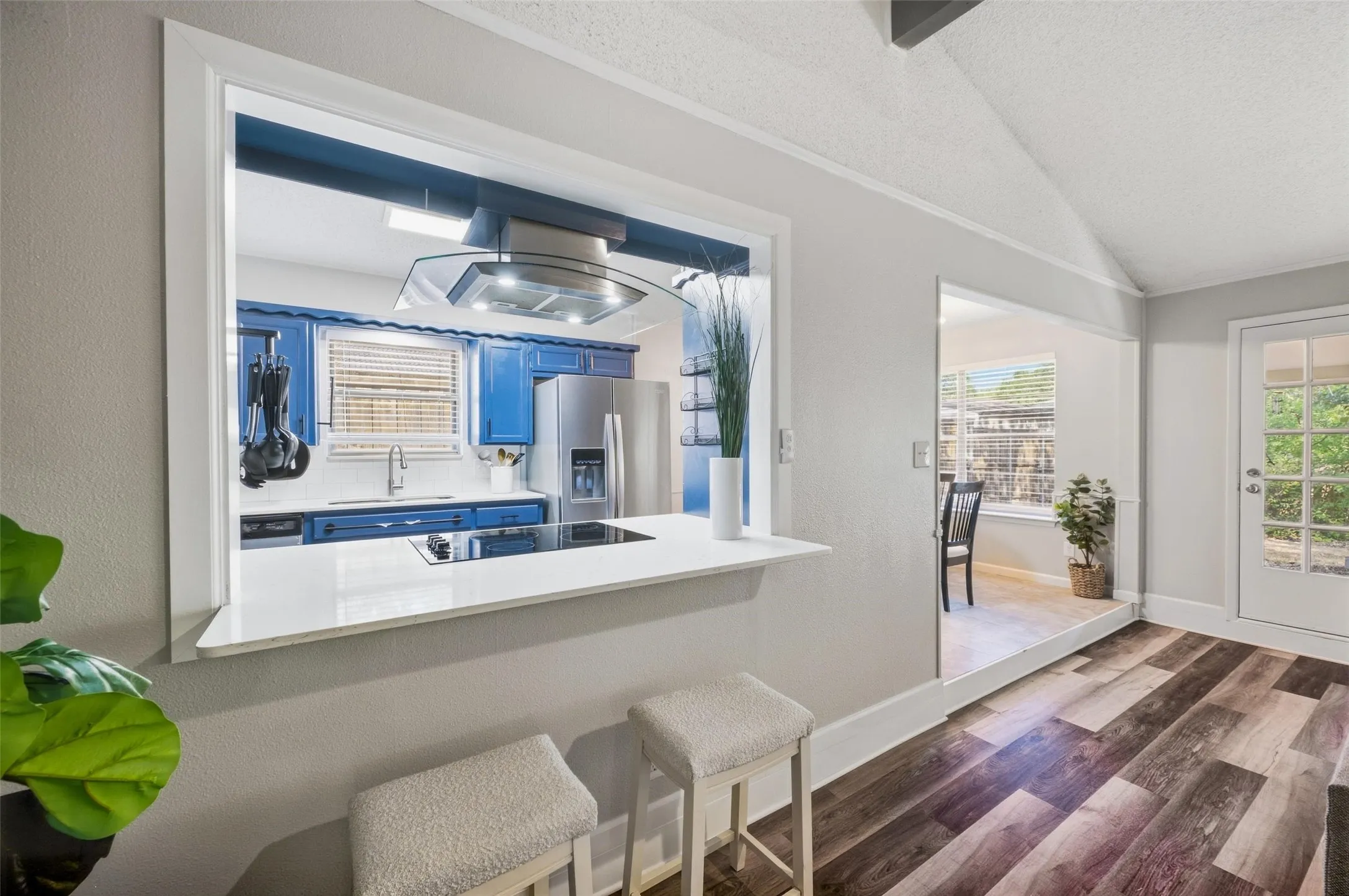 Pass-through window with seating, wood-finish flooring, glass-paneled exterior door, modern kitchen appliances, and recessed lighting