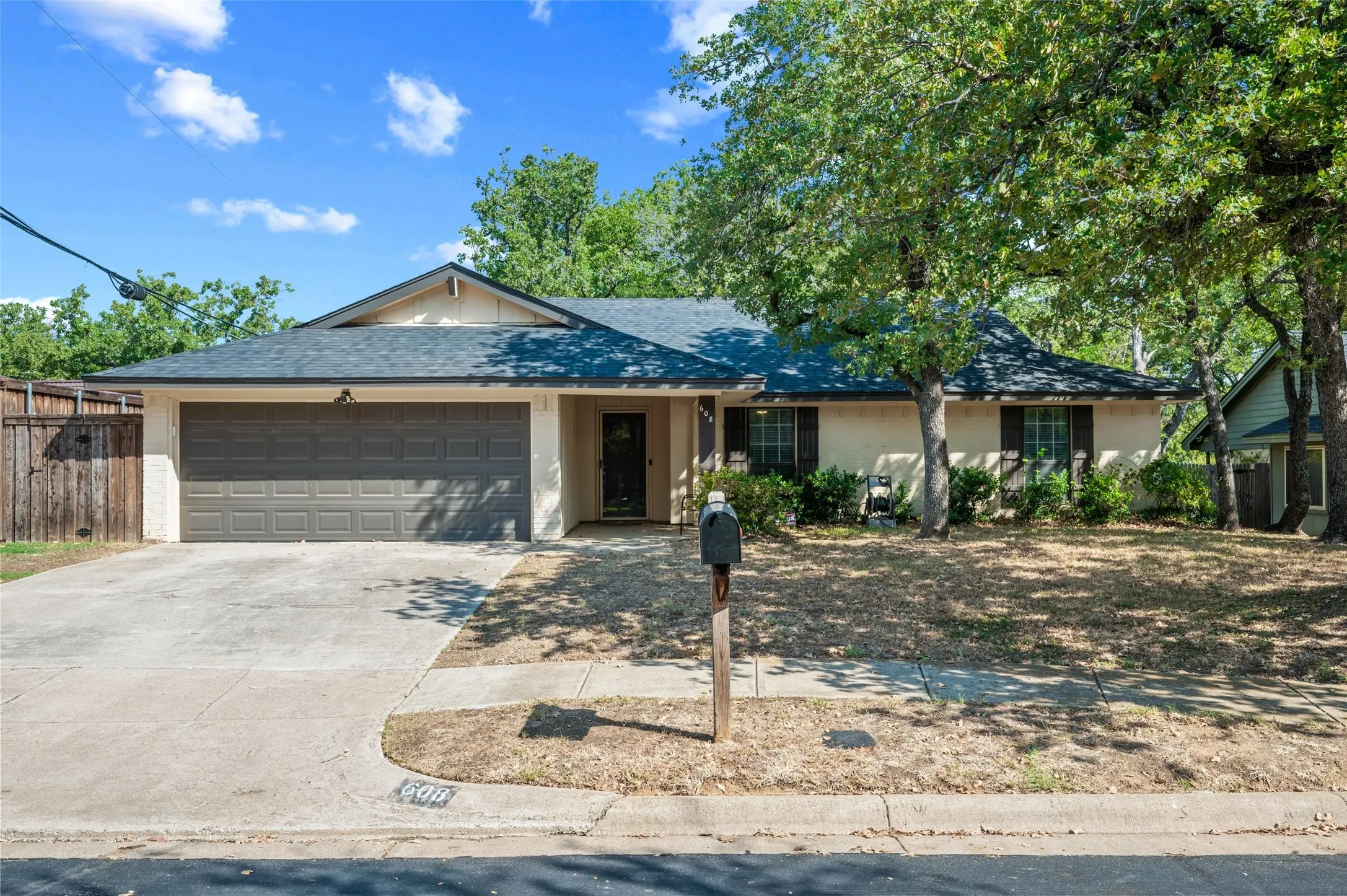 Single-story residence featuring a two-car garage, concrete driveway, and mature landscaping