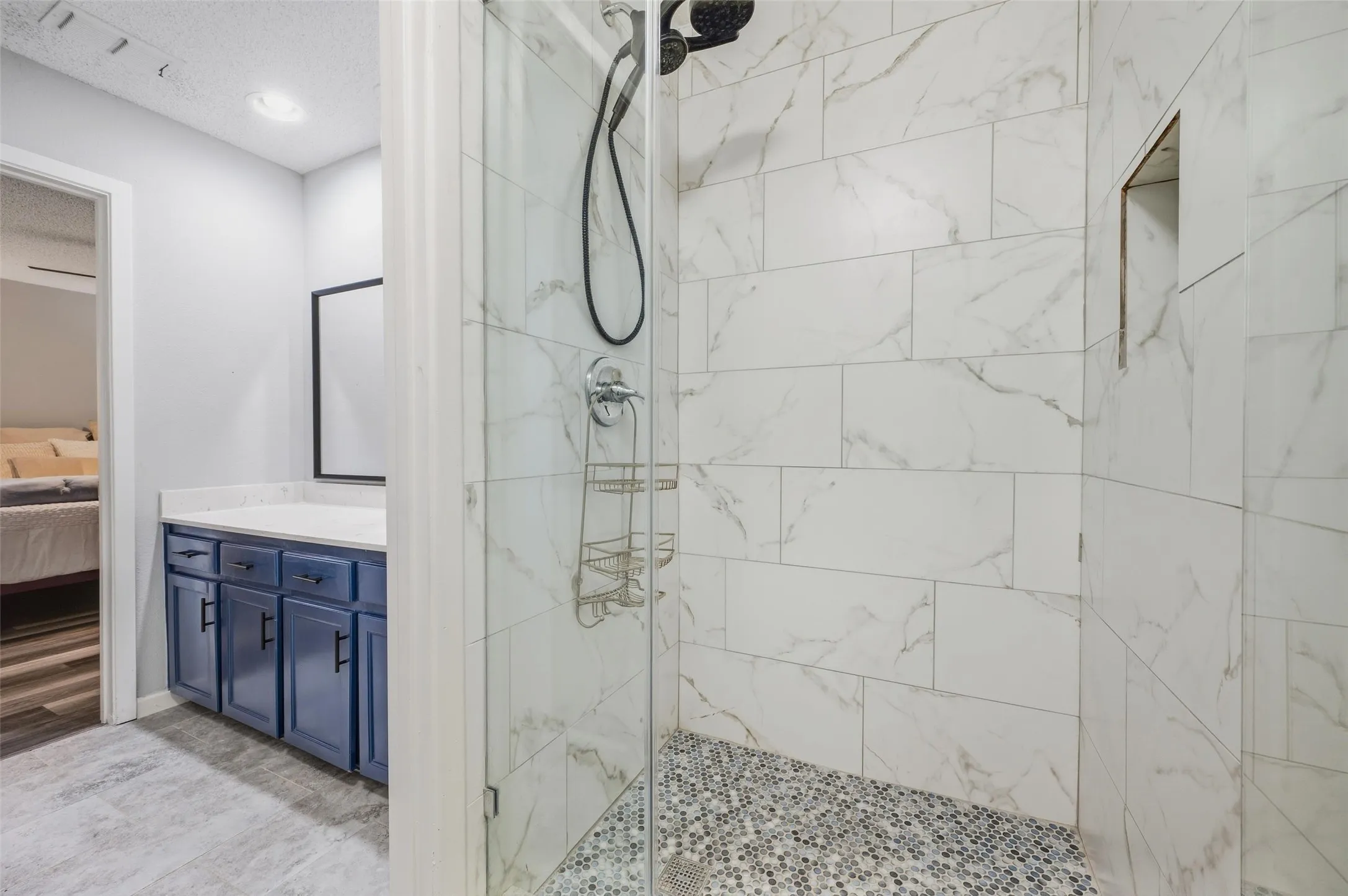 Walk-in shower with clear glass enclosure and mosaic tile floor