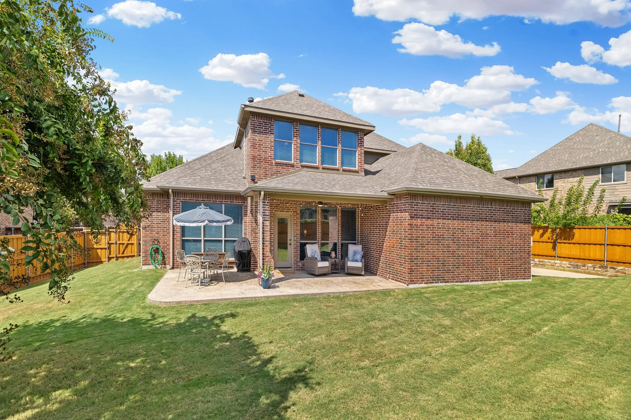 A great view from the backyard looking back towards the house.  Love seeing all that low maintenance brick and upgraded stamp concrete patio.