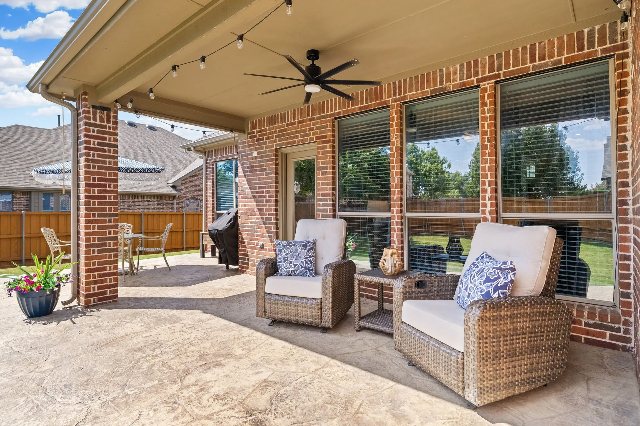 And now to the wonderful backyard!  This covered patio is perfect for enjoying views of the huge backyard and the stamped concrete adds to the ambience.  Enjoy the ceiling fan, string lights and separate eating and BBQ area as well.