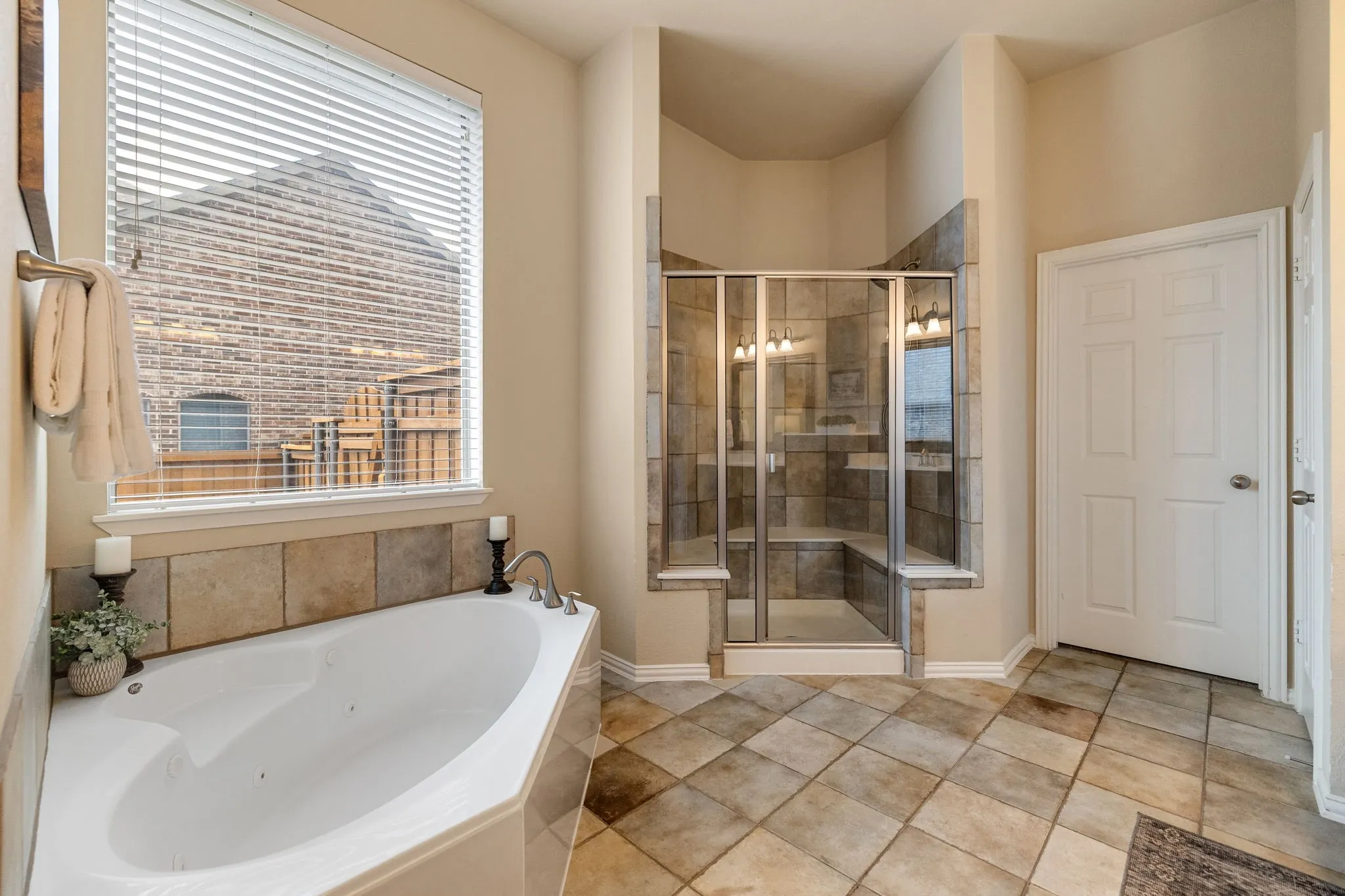 Corner jetted soaking tub & separate glass-enclosed shower with built-in bench seating.