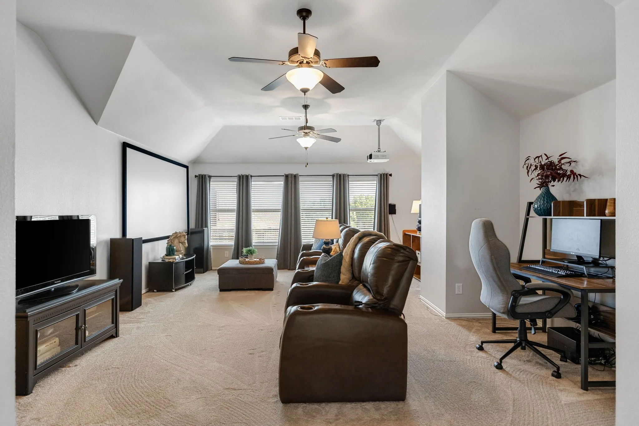 Now let's head on upstairs where you will find a vast gameroom at the top of the stairs.  Impressive vaulted ceilings with multiple ceiling fans & bank of windows add to the openness of the room.