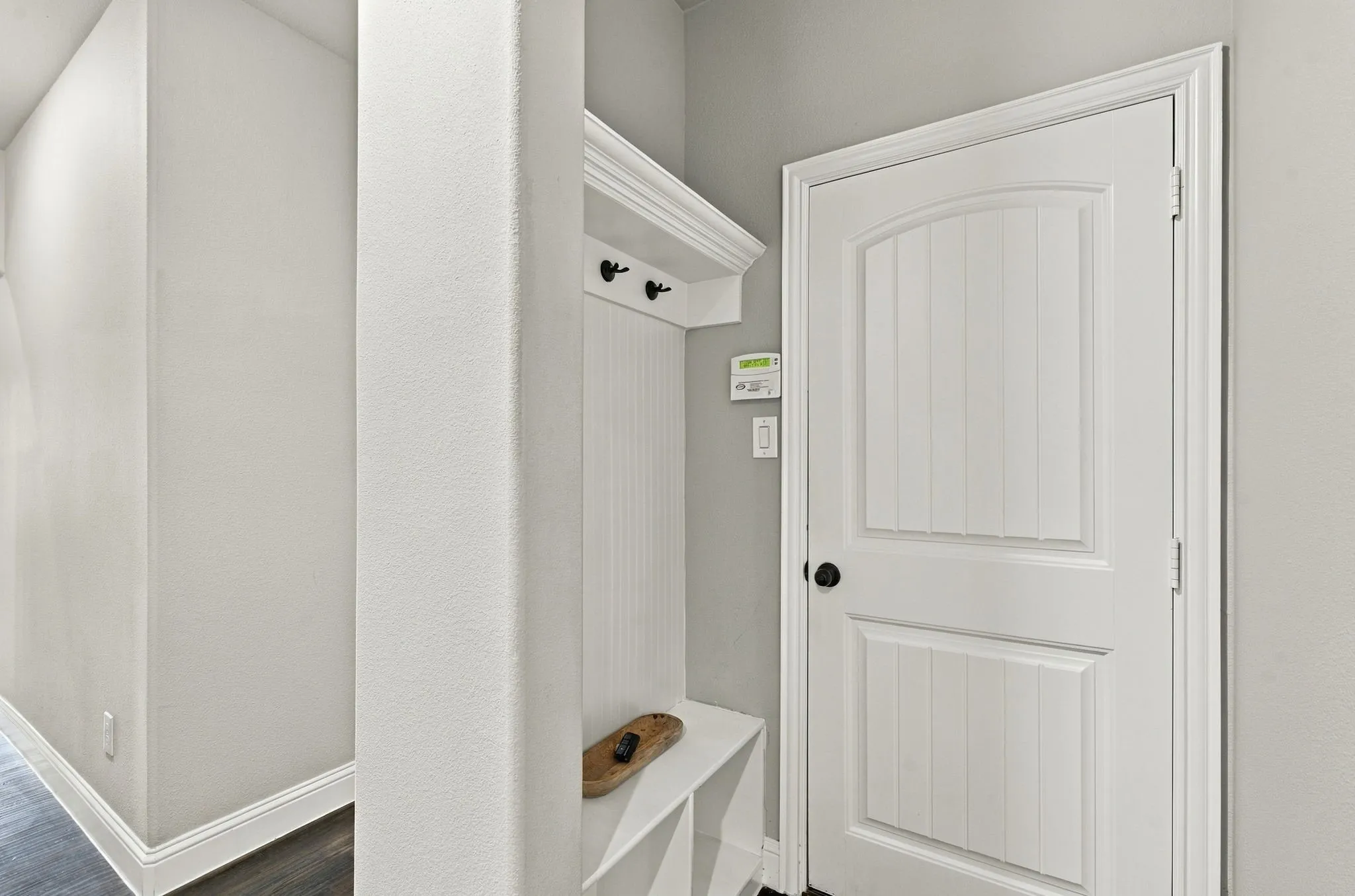 Built-in hall tree with bench seating, beadboard backing, and black hooks