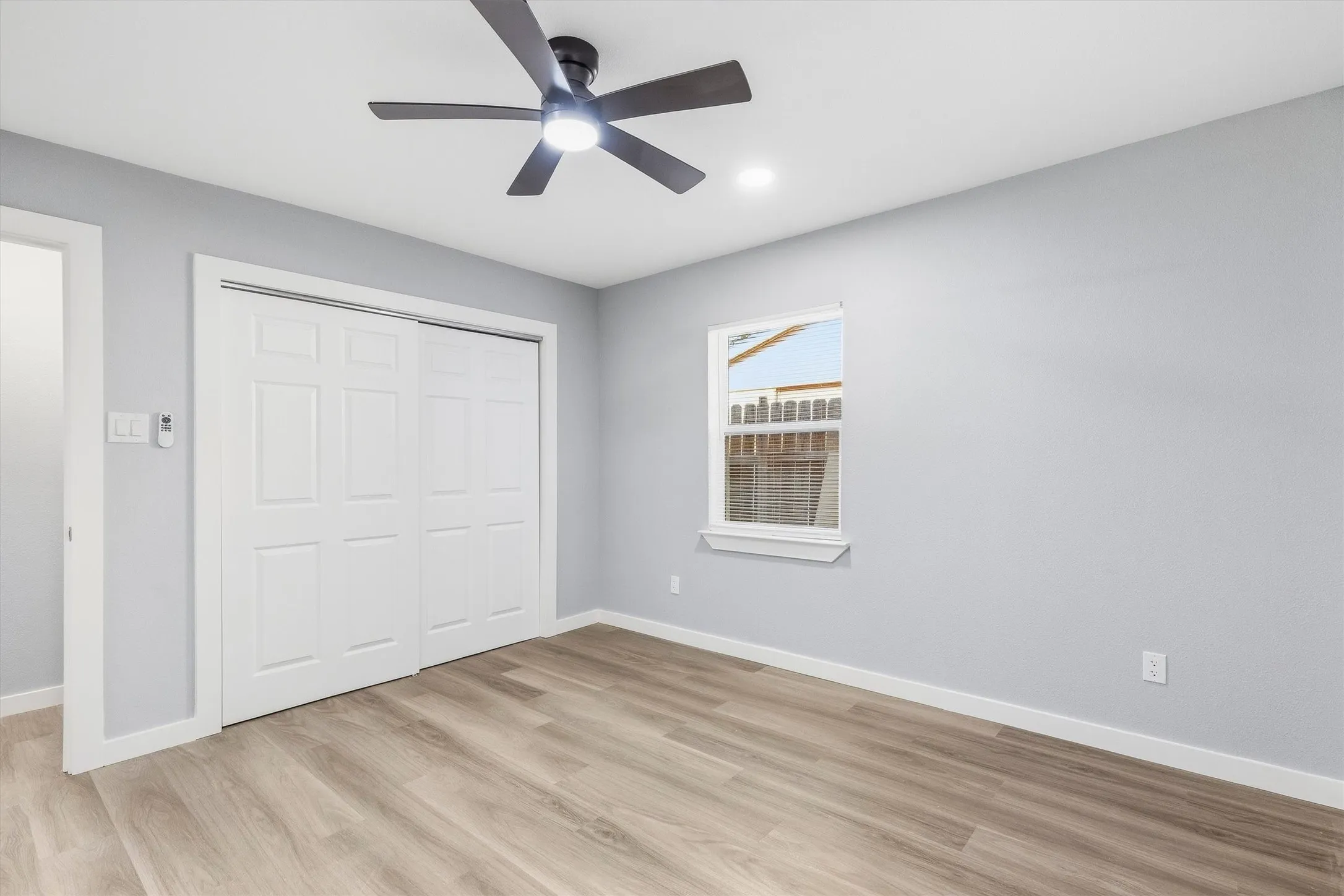 Wood-finish flooring, ceiling fan with integrated lighting, recessed lighting, and a window with white trim