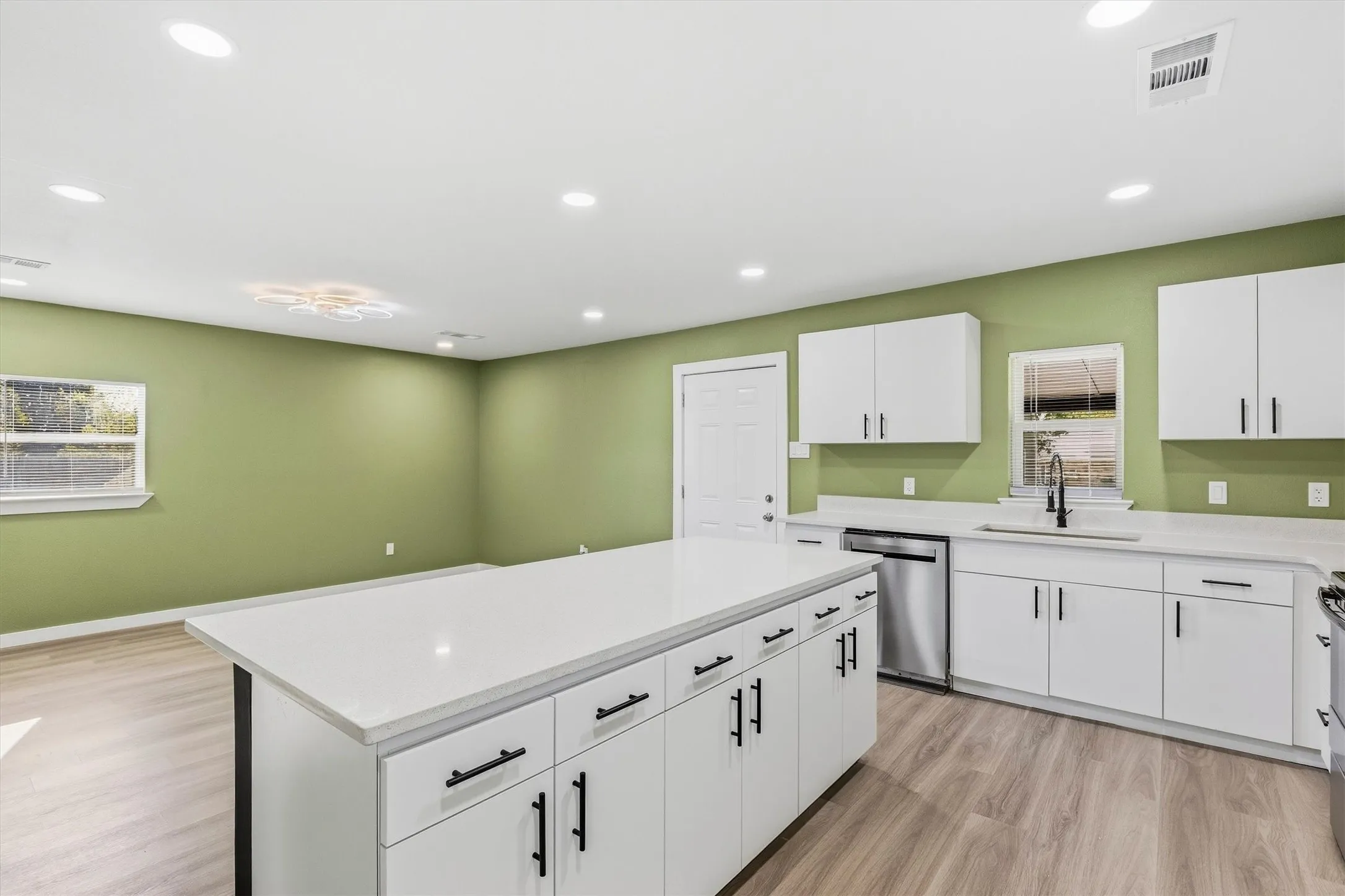 Kitchen featuring a large island with white cabinetry, stainless steel appliances, and wood-finish flooring