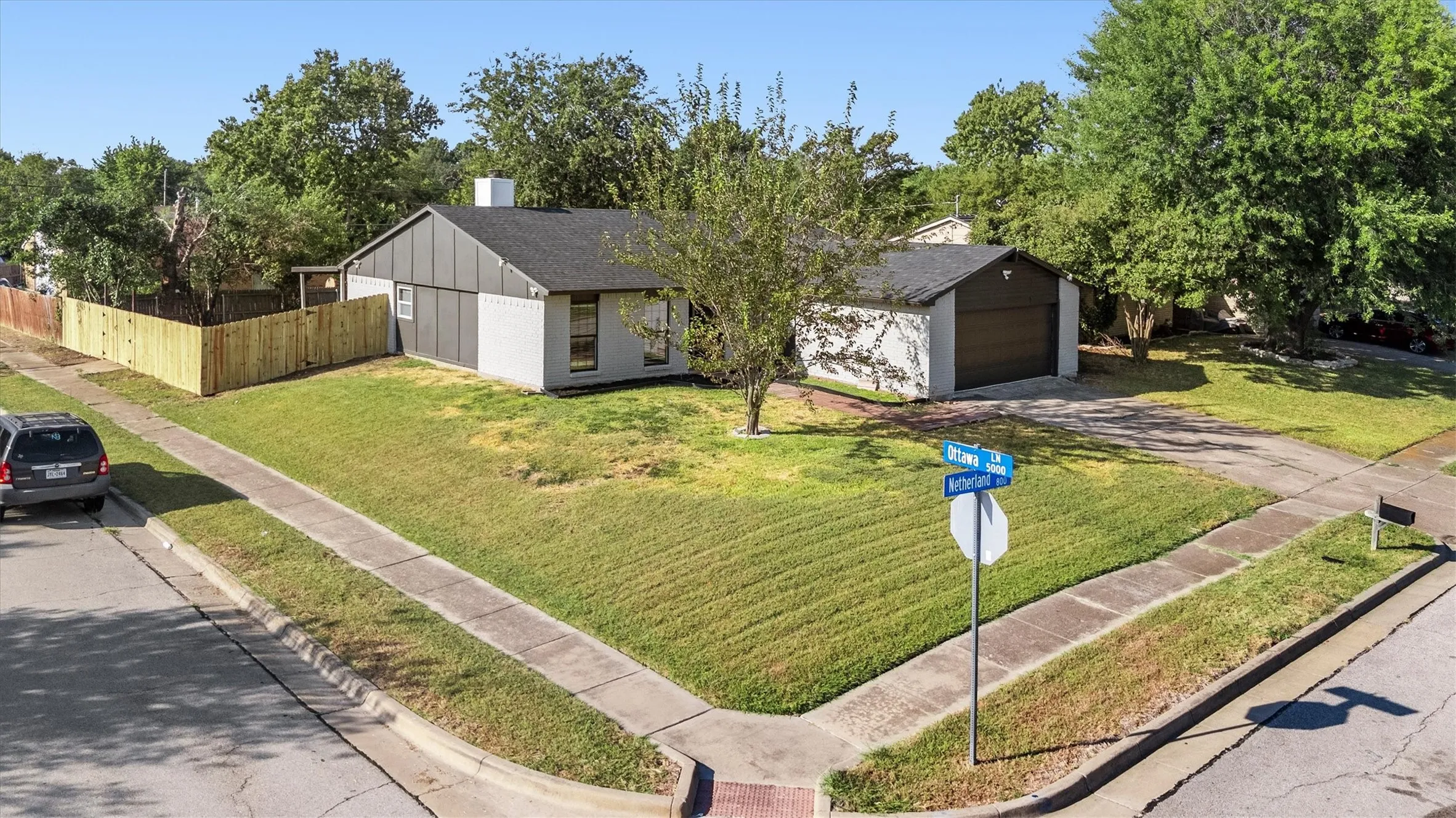 Corner lot property with a detached two-car garage, partial privacy fencing, and mature trees