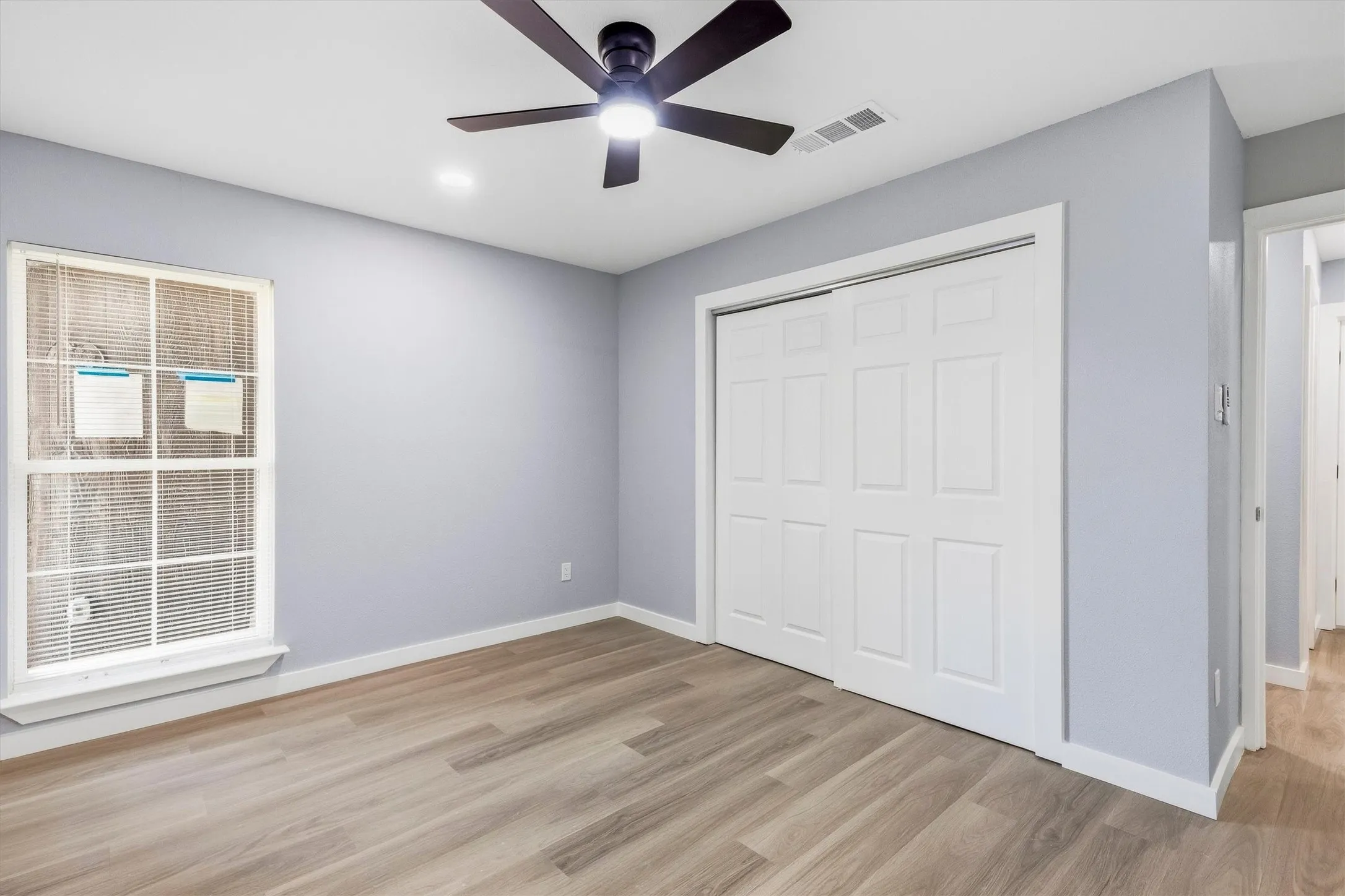 Wood-finish flooring, ceiling fan, recessed lighting, double sliding closet doors, and a window with blinds