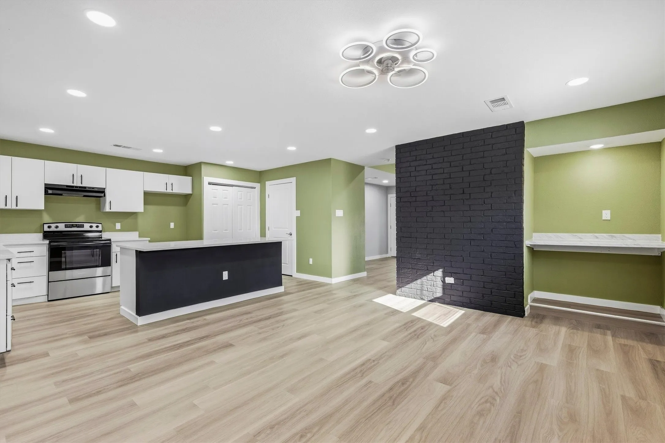 Open-concept living space with wood-finish flooring, recessed lighting, and a modern ceiling fixture
