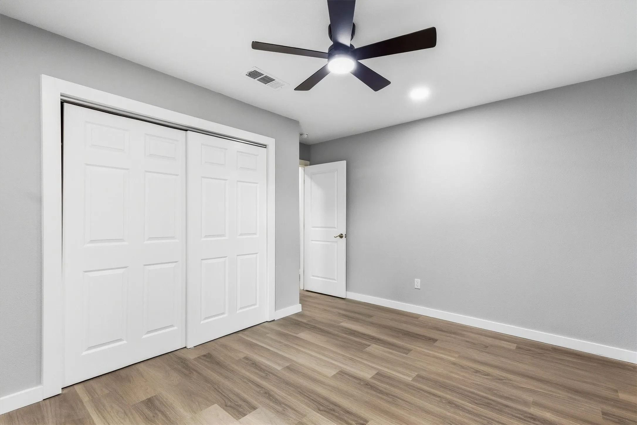 Wood-finish flooring, recessed lighting, ceiling fan, and white paneled doors