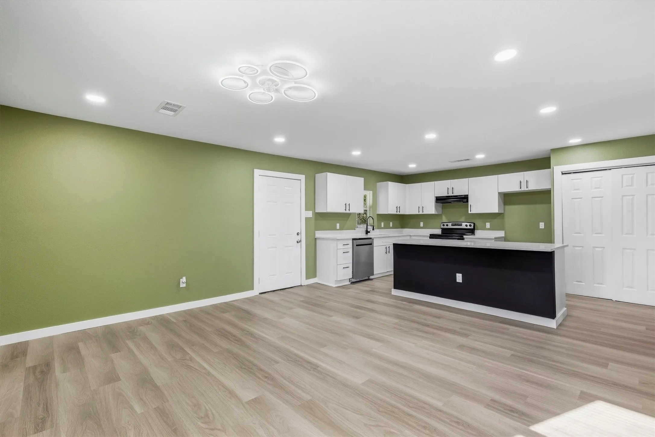 Open-concept living area with wood-finish flooring, recessed lighting, and a contemporary ceiling fixture