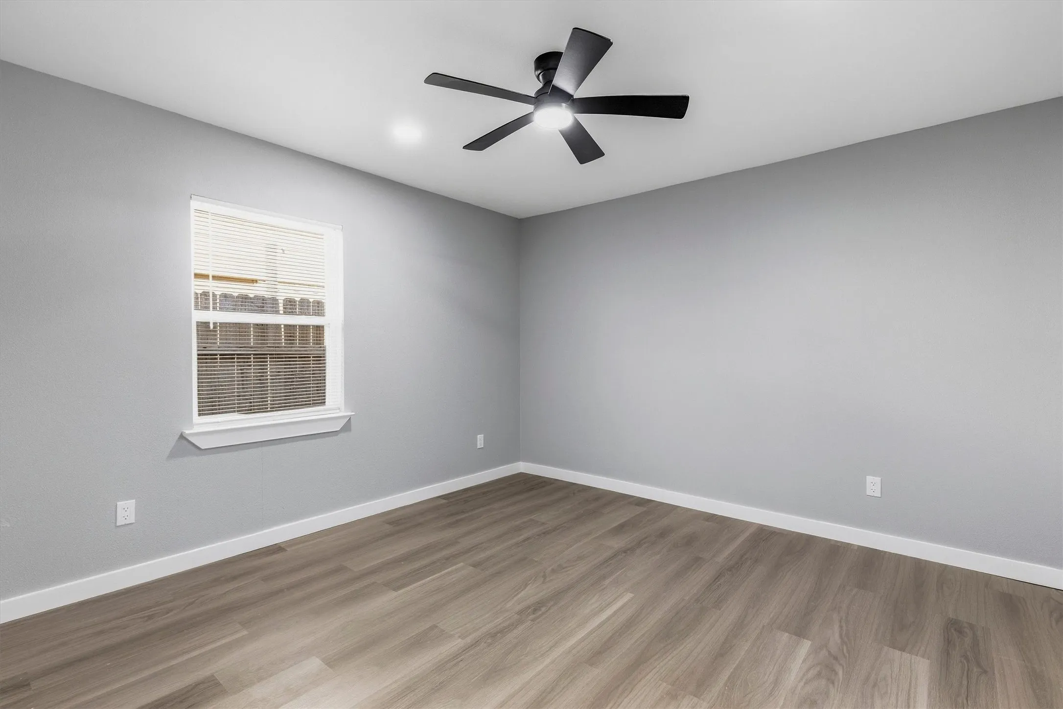 Recessed ceiling lighting, wood-finish flooring, white window trim, and a black ceiling fan with integrated light