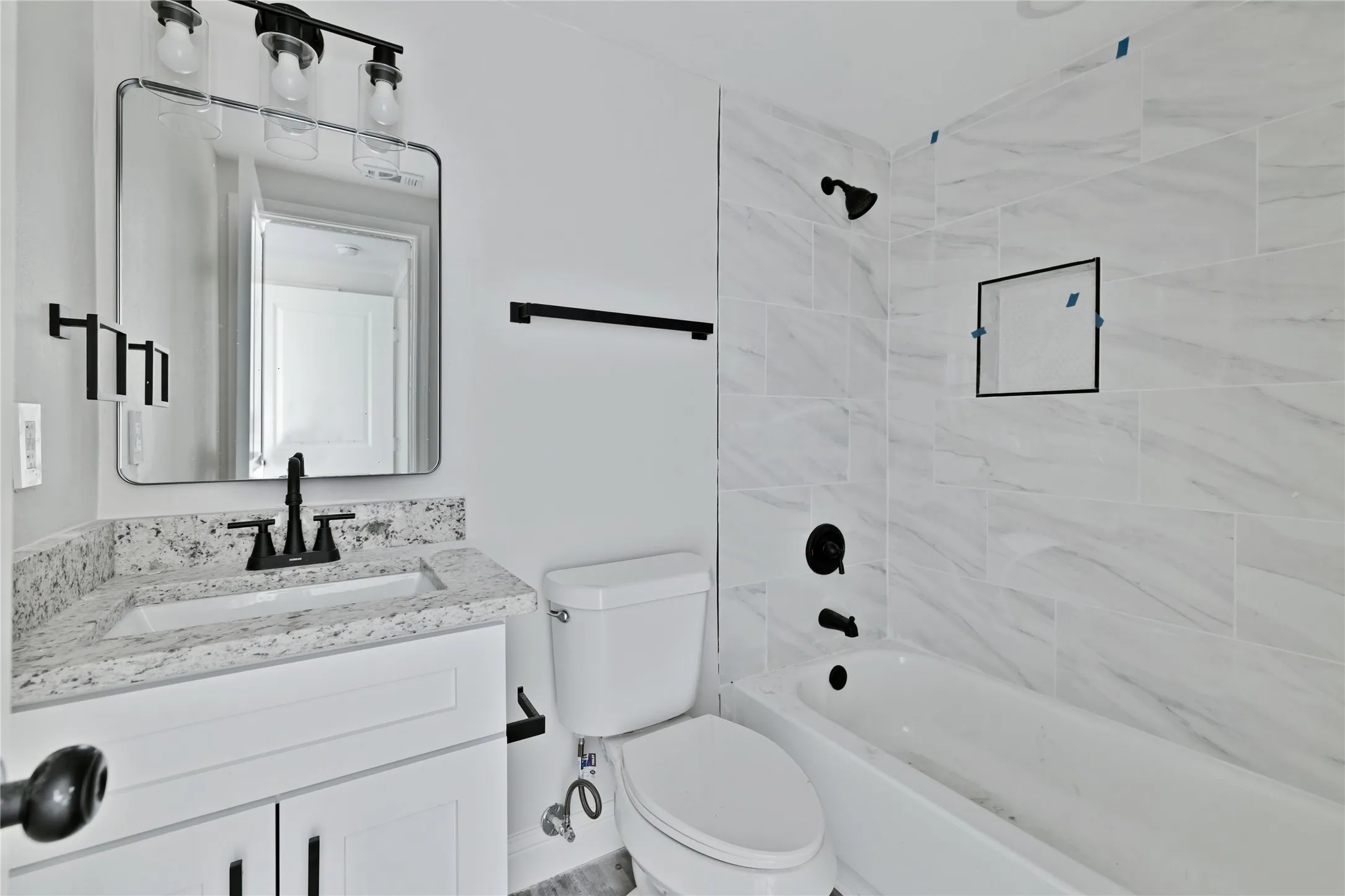 White vanity with black hardware, stone-finish countertop, and undermount sink