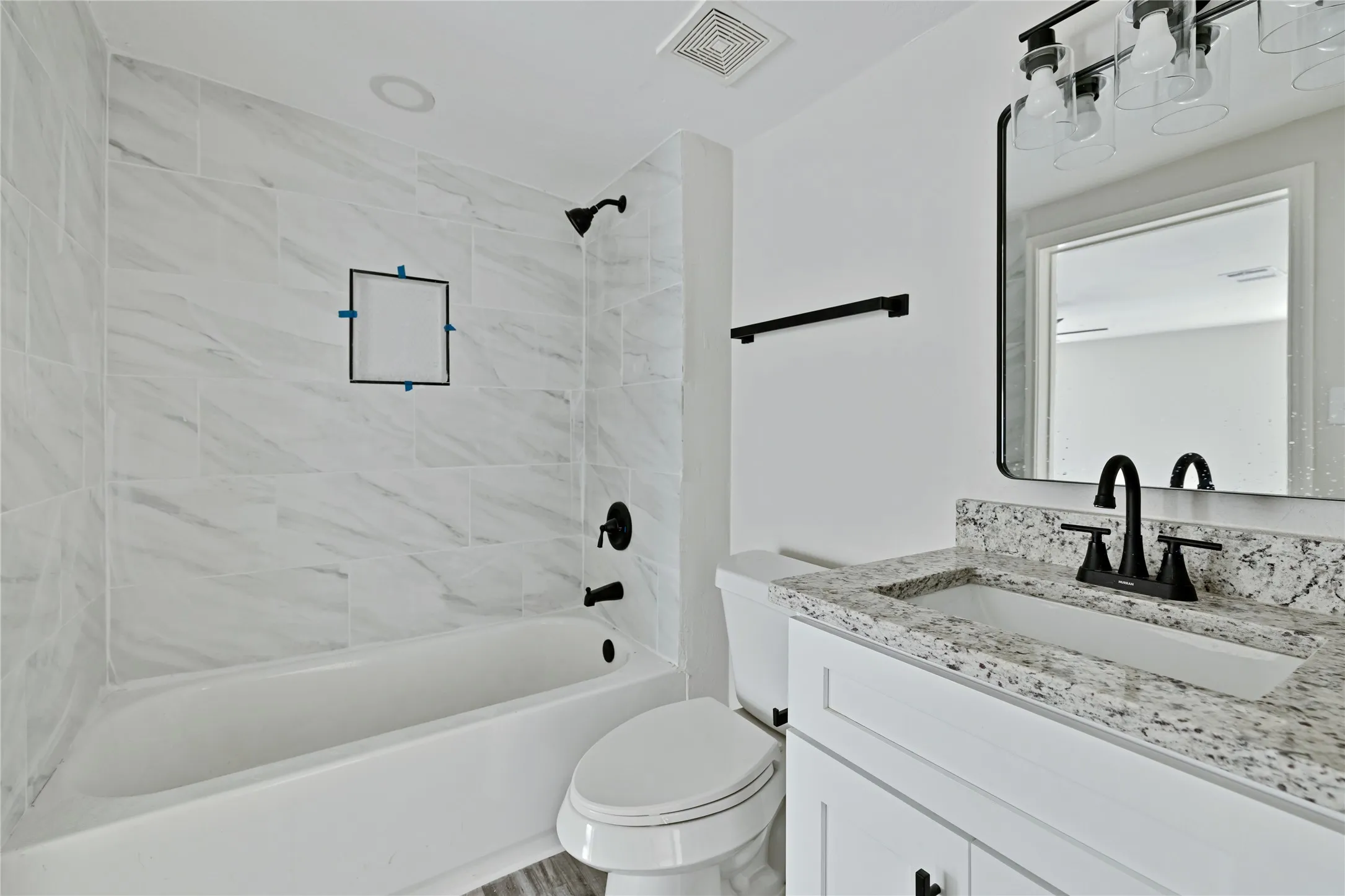 White vanity with a granite countertop, undermount sink, and matte black faucet