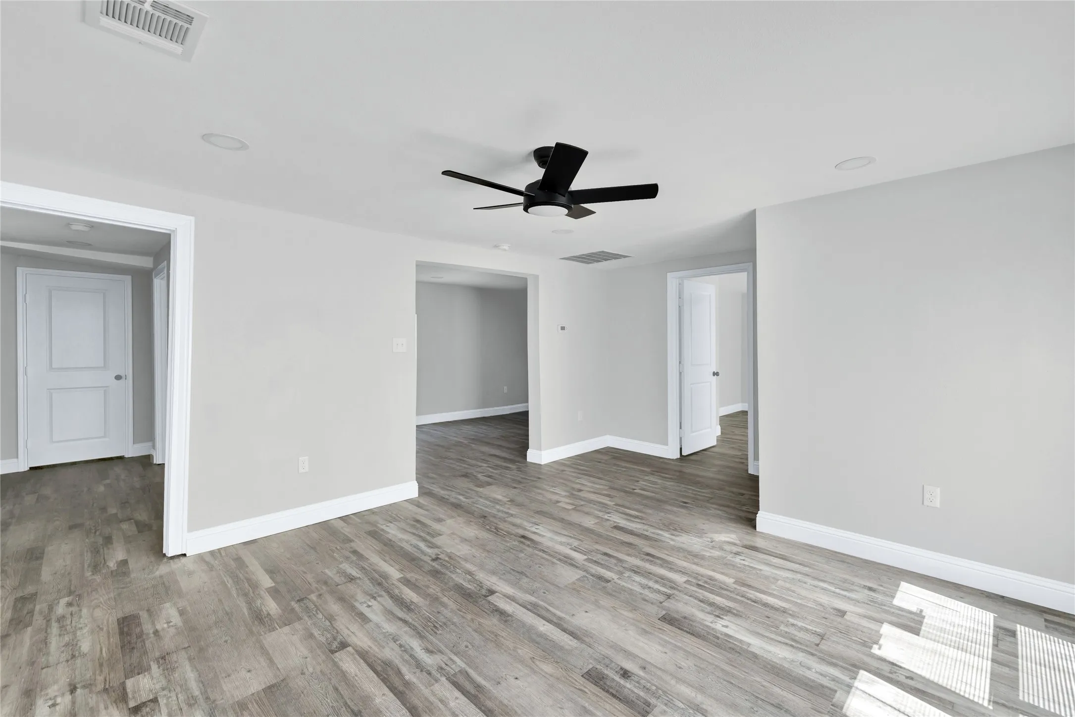 Wood-finish flooring, recessed lighting, ceiling fan, and white trim