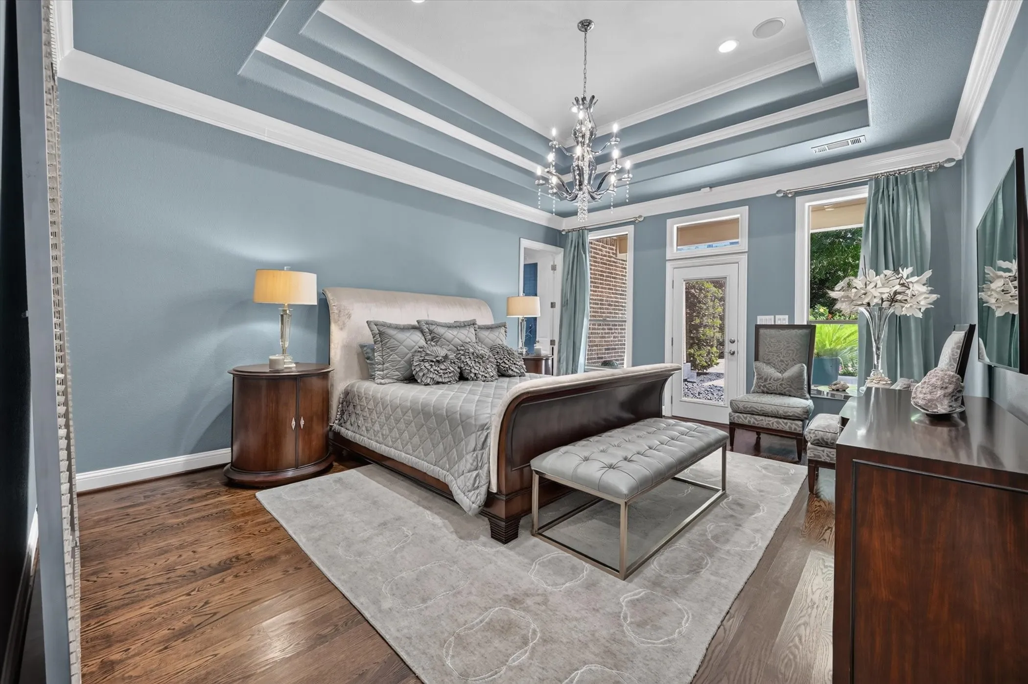 Tray ceiling with crown molding, hardwood flooring, chandelier lighting, and French door access to outdoor space